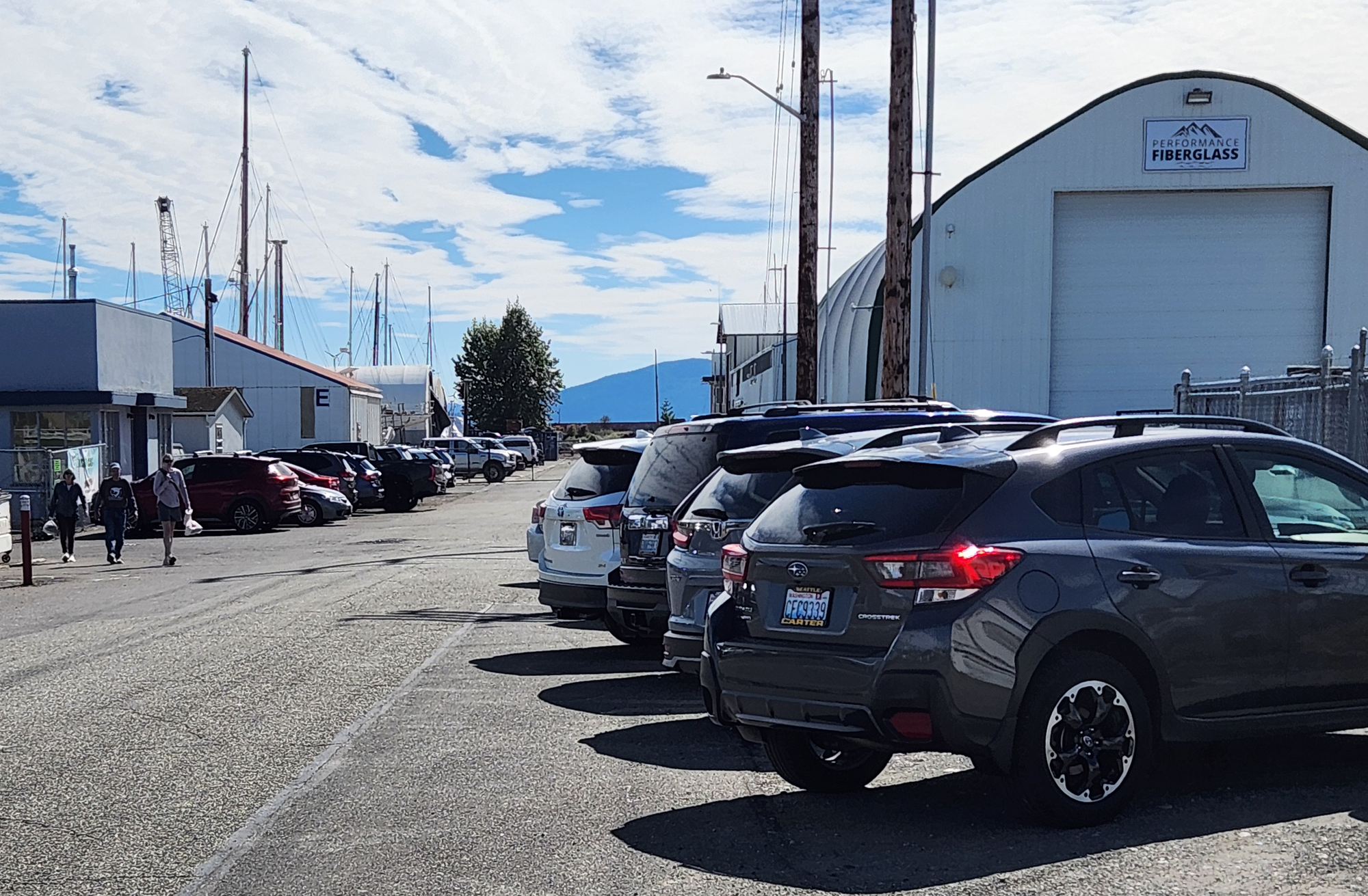A dozen or so parked cars on an industrial street.