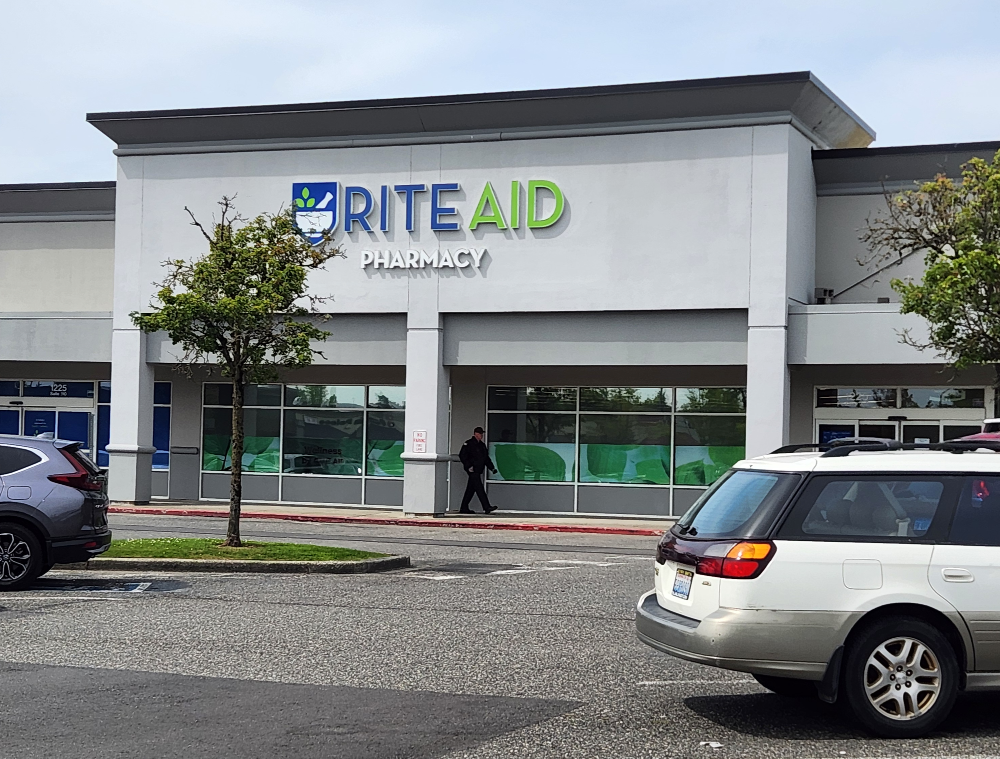 The exterior of the Rite Aid location at the Sunset Square shopping center with a white Subaru parked in the foreground.