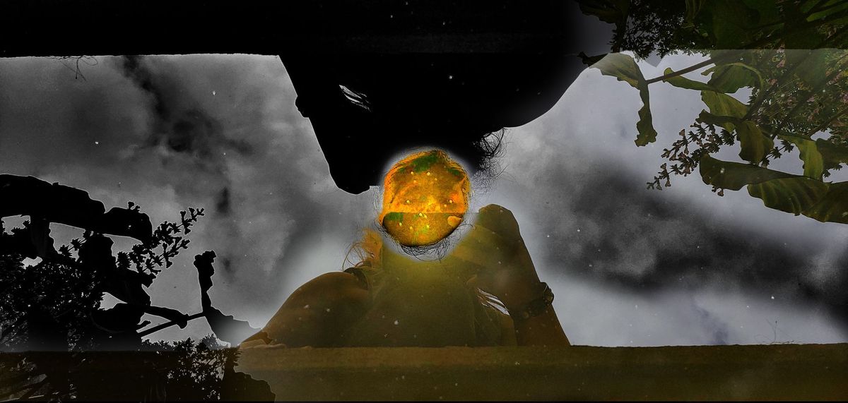 A picture of me leaning over my reflection in a pond. The image is doubled, with a bright spot where the two faces intersect.