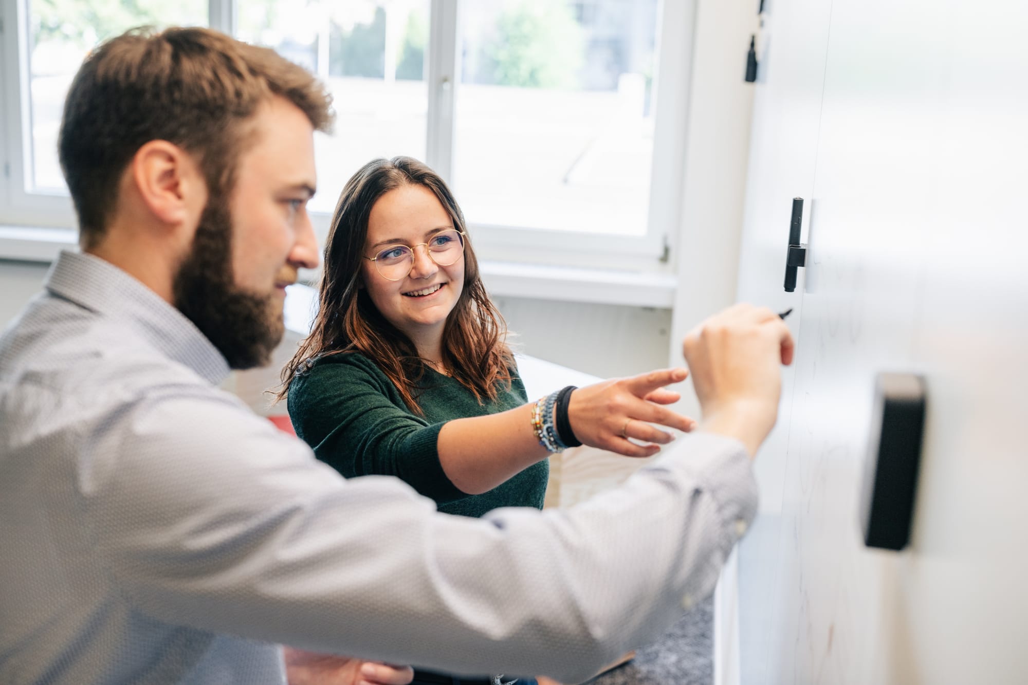 instride Mitarbeiterin Cami erklärt auf Whiteboard die Projektplanung Dave