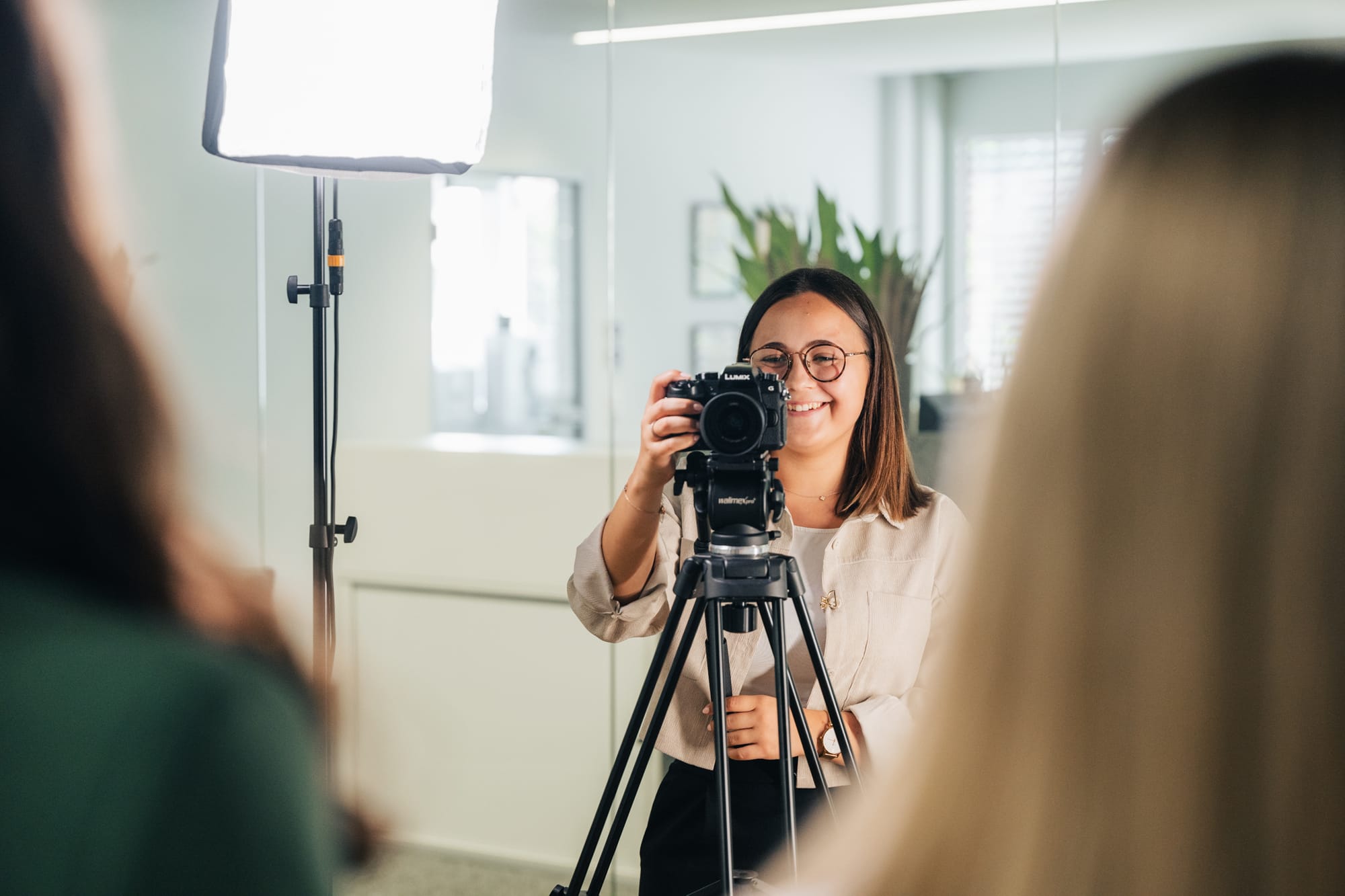 instride Mitarbeiterin Livia steht an Kamera und fotografiert zwei weitere Kolleginnen.