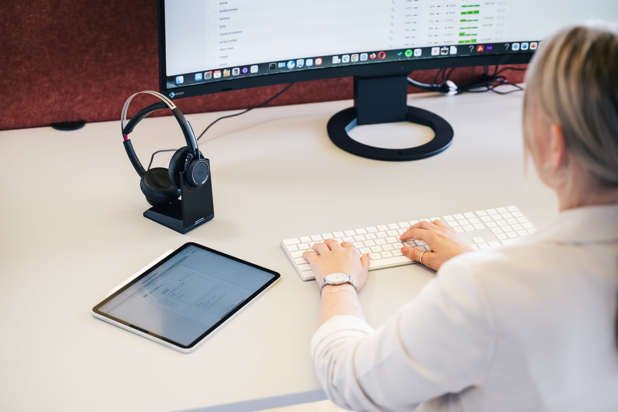 SEO-Spezialistin steht an ihrem Pult und betreibt eine Recherche in Sistrix. Neben ihr liegt ein iPad und ihr Headset.