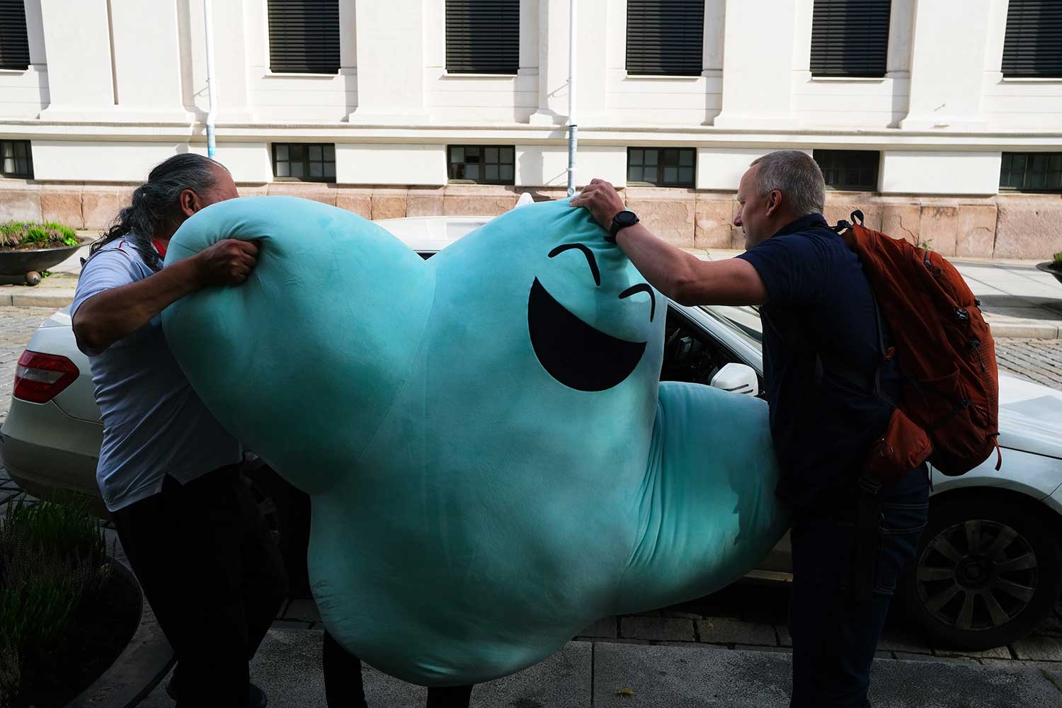 Fotografi av daglig leder av Fiken som sammen med en sjåfør prøver å få plass til Fikens maskott i en taxi
