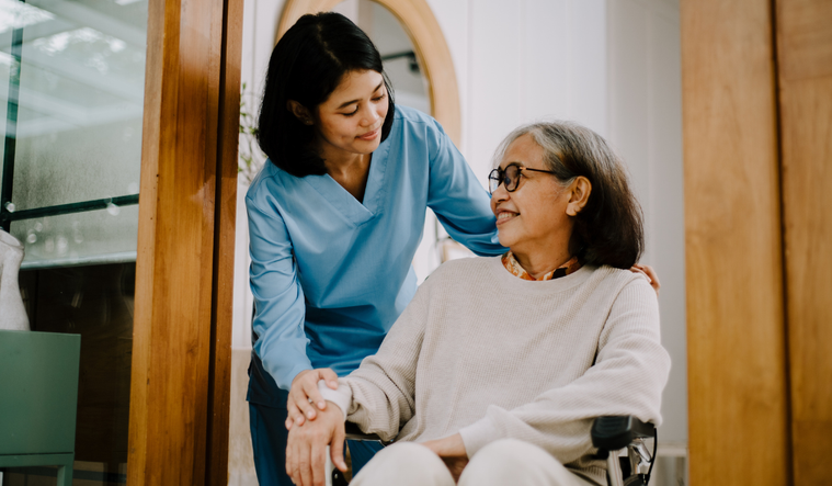 caregiver helps woman in wheel chair
