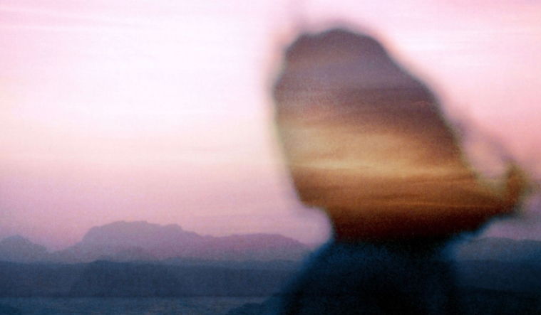 Outline of a woman overlooking a sunset.