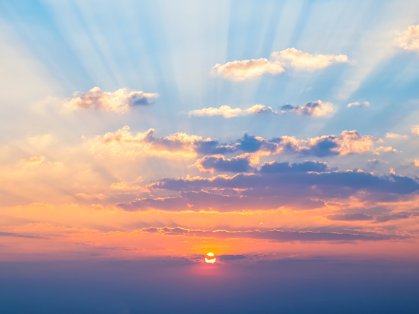 Bright sunrise with clouds and rays of light peaking through.