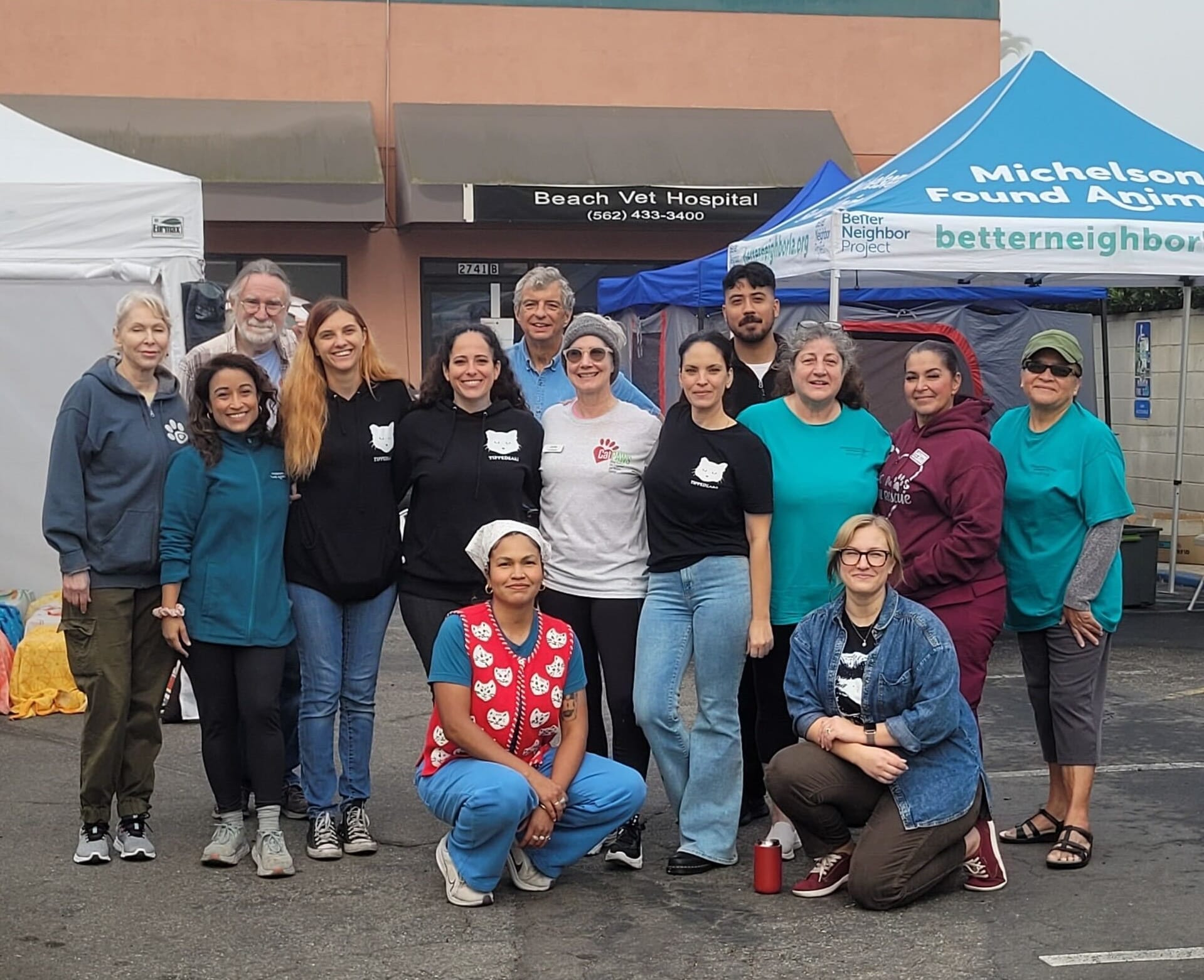 About a dozen people pose for a photo in a parking lot.