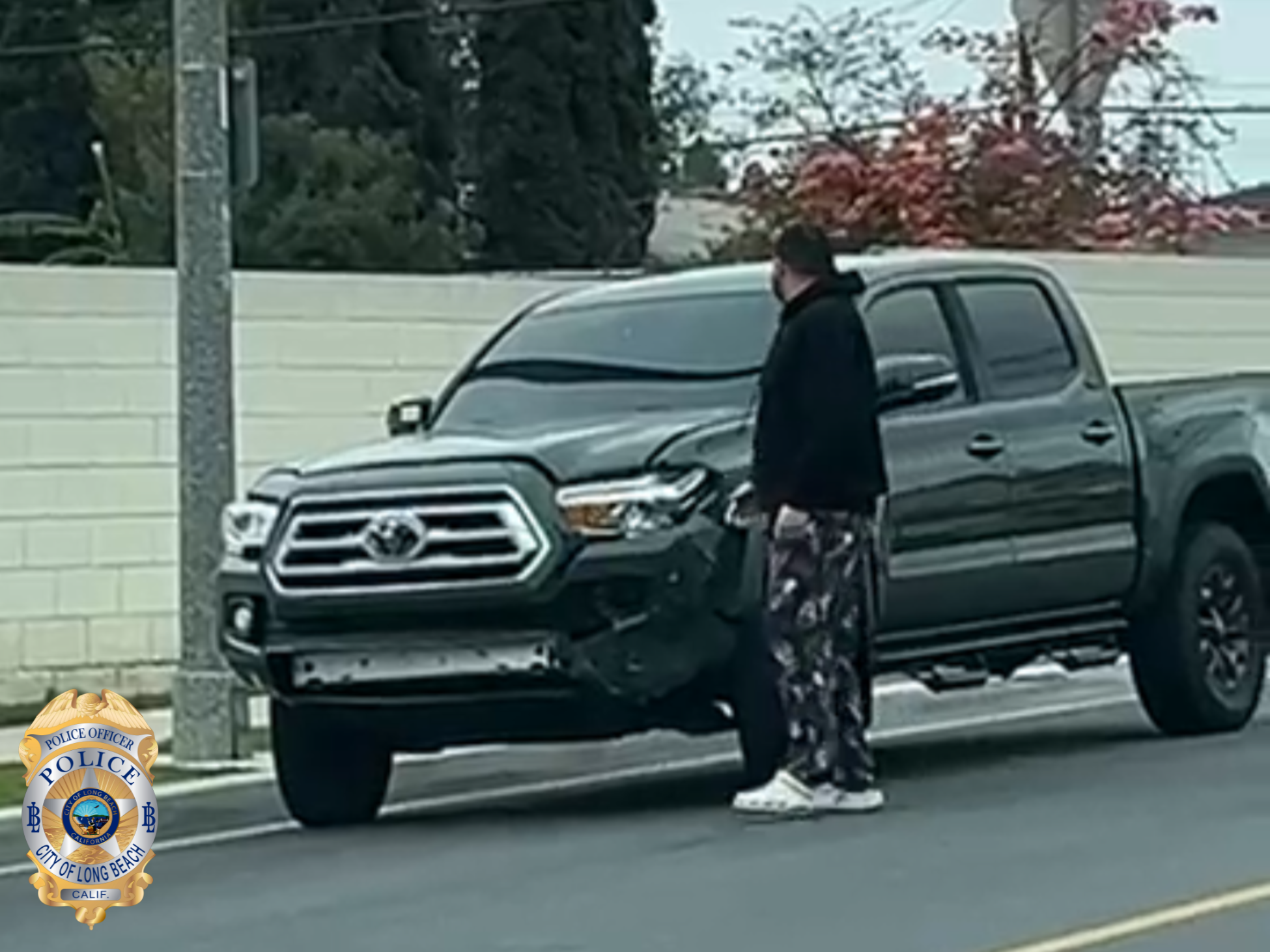 Blurry photo of a man in dark clothes standing next to a dark colored pickup truck.