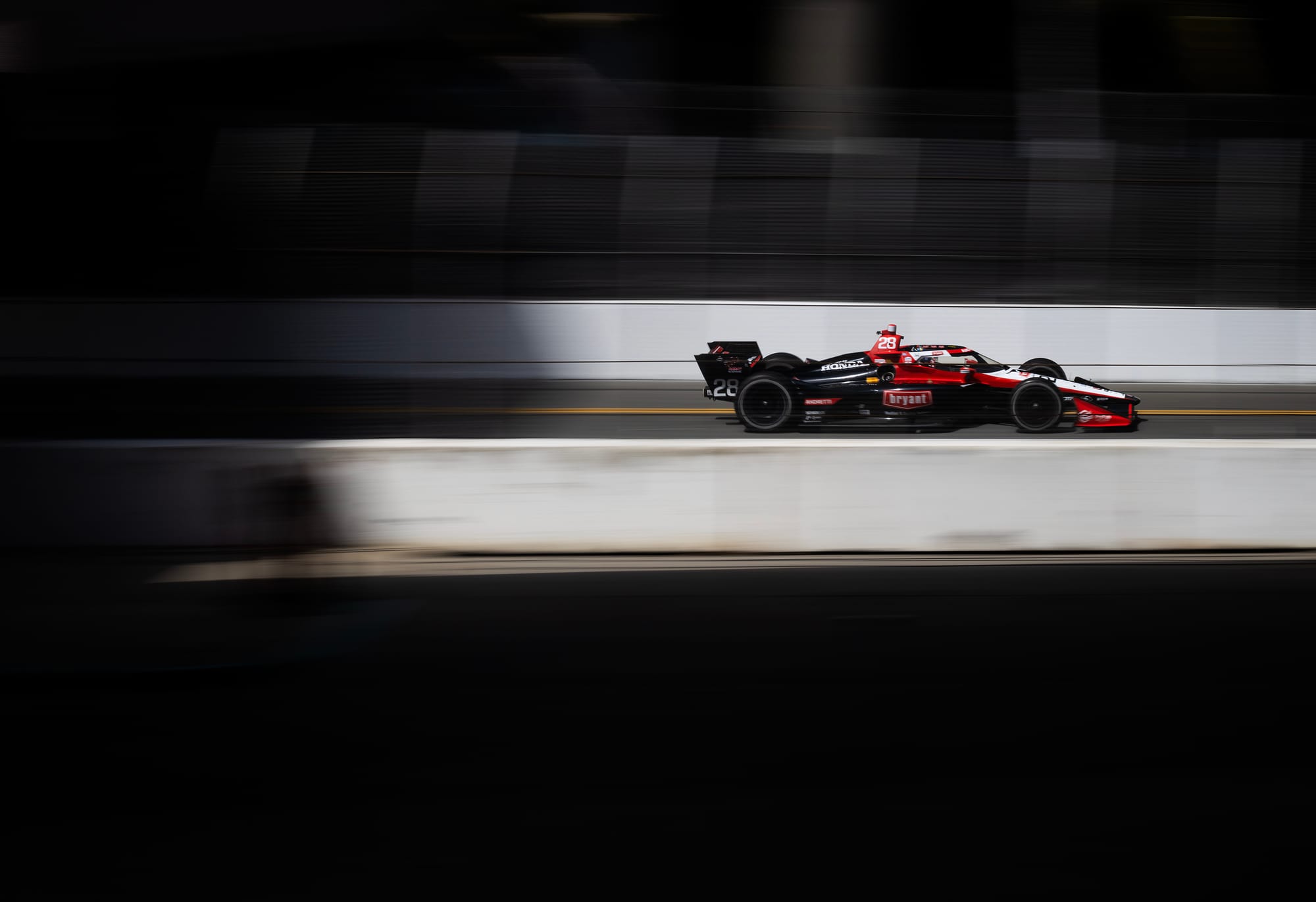 A red and black race car drives on a race track.