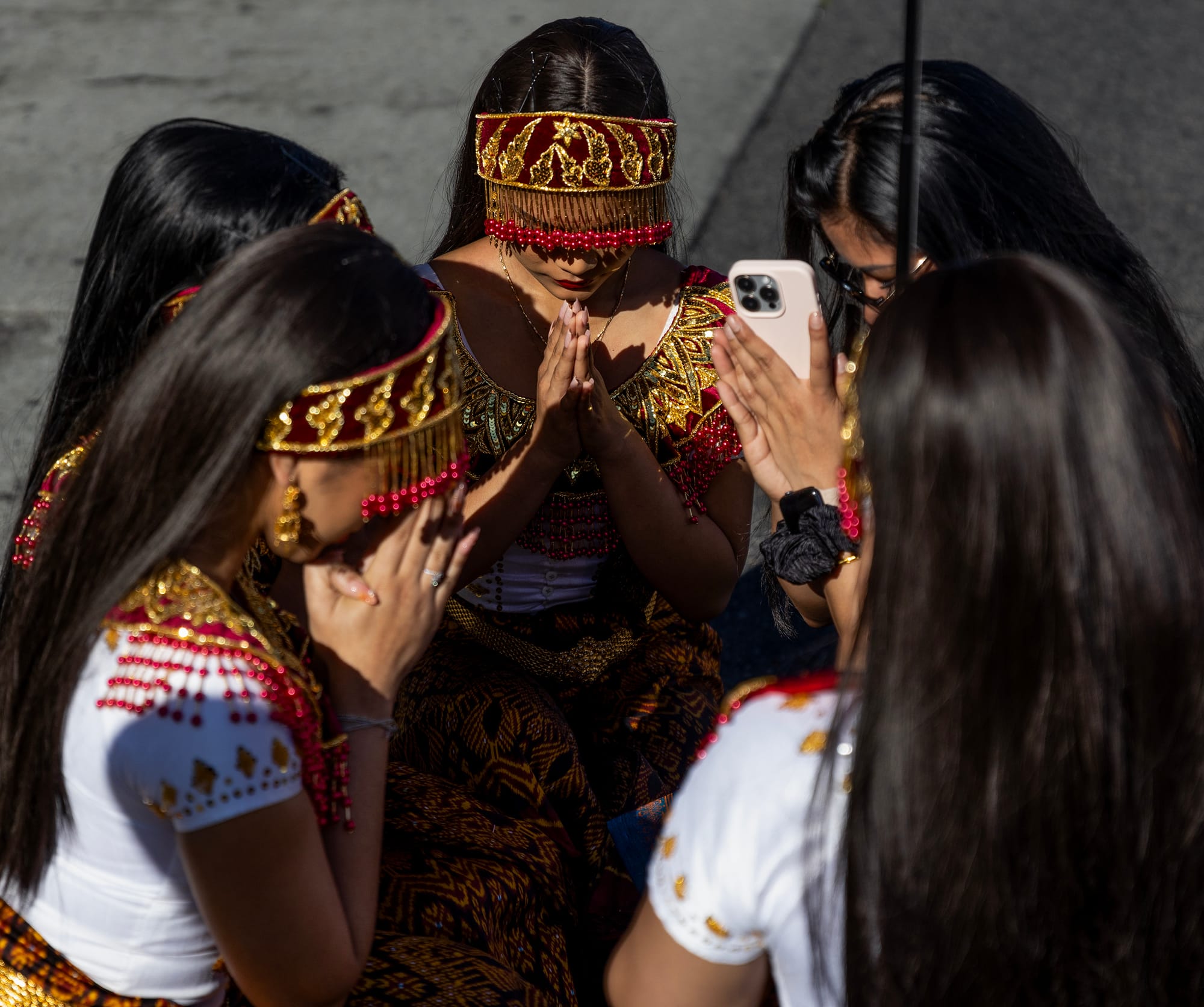 Five women with long dark hair stand together.