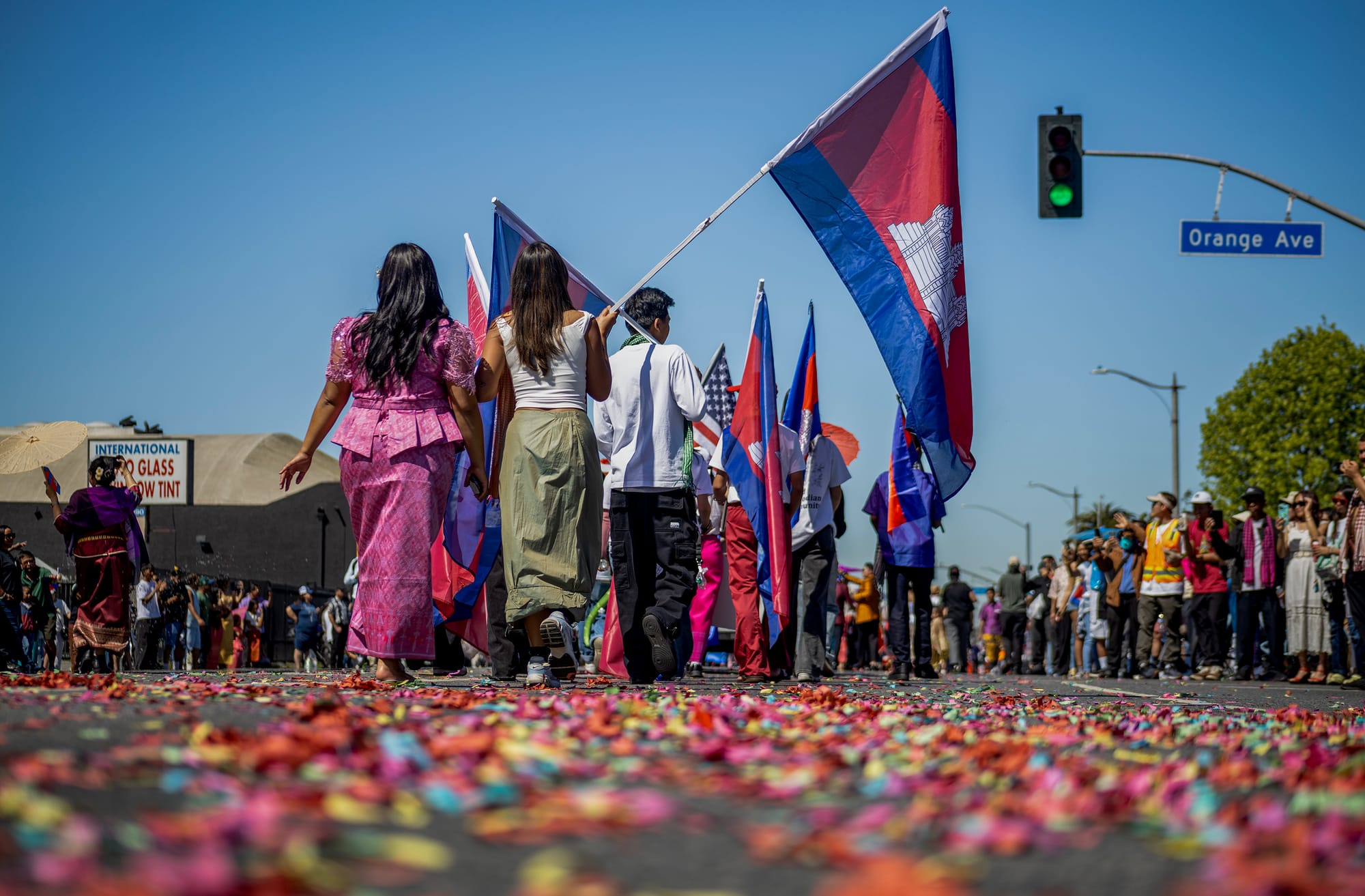 People holding flags walk over a street covered in confetti.