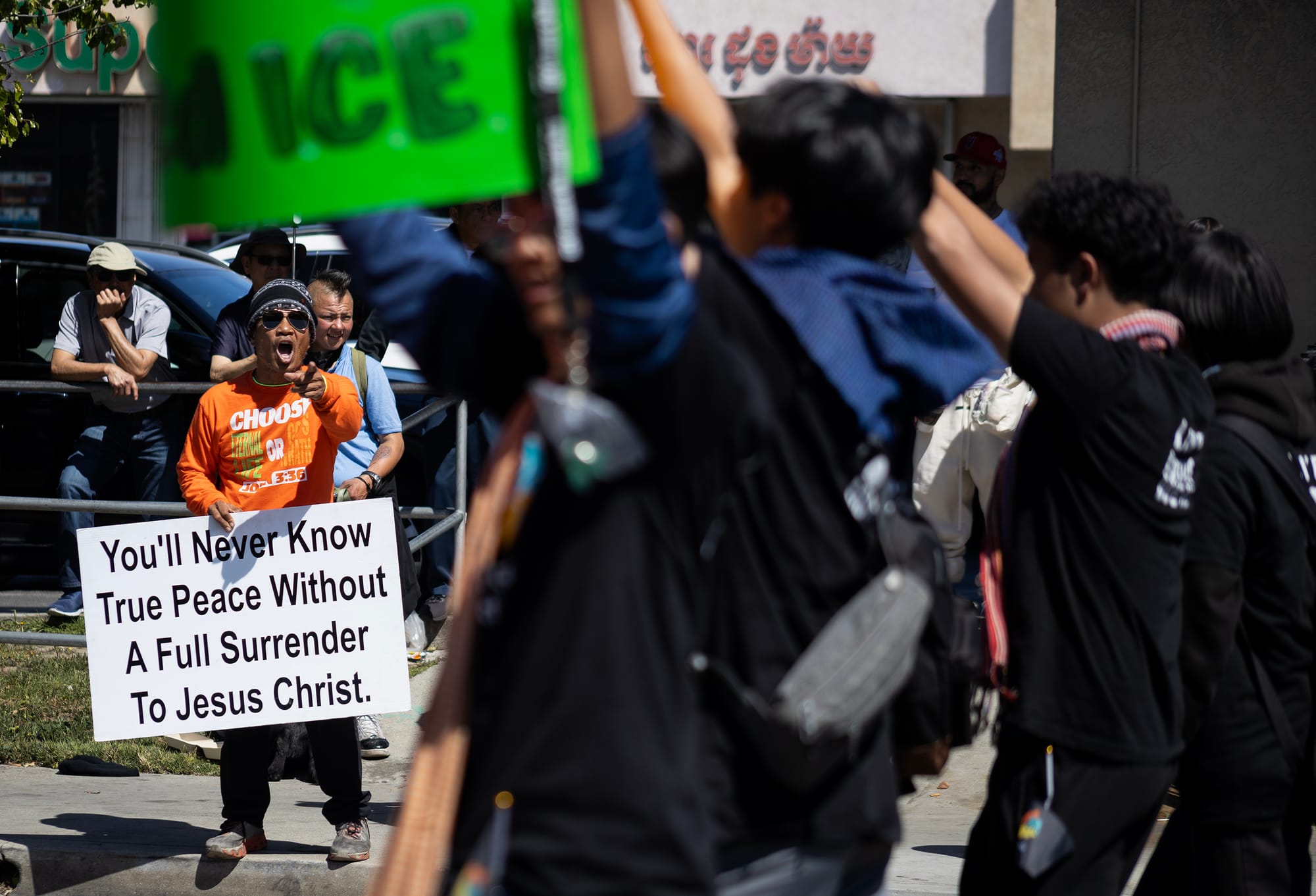 A man holding a sign yells at a group of people.