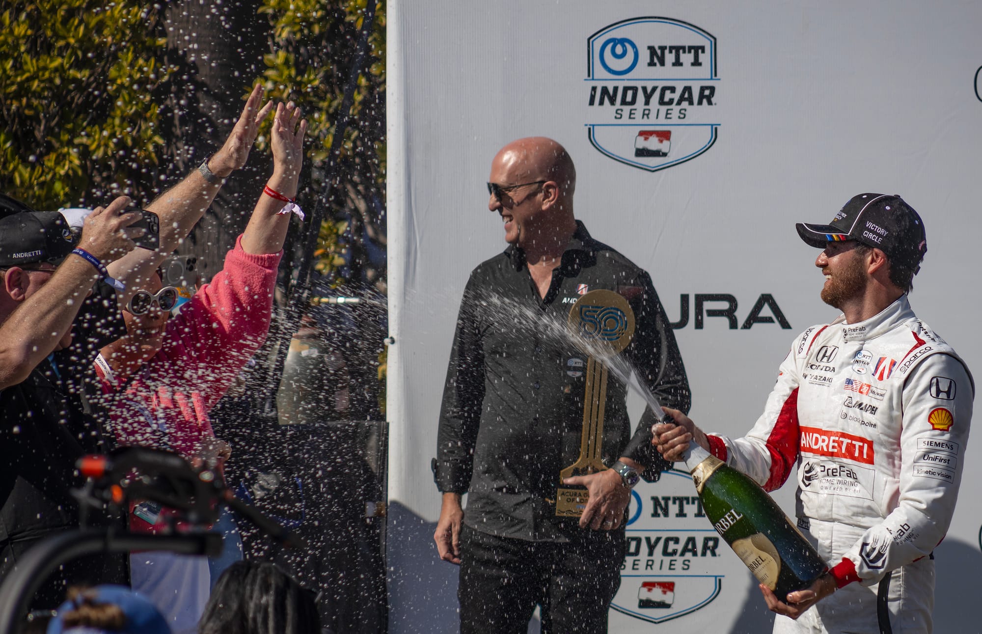 A man sprays a crowd with champagne.