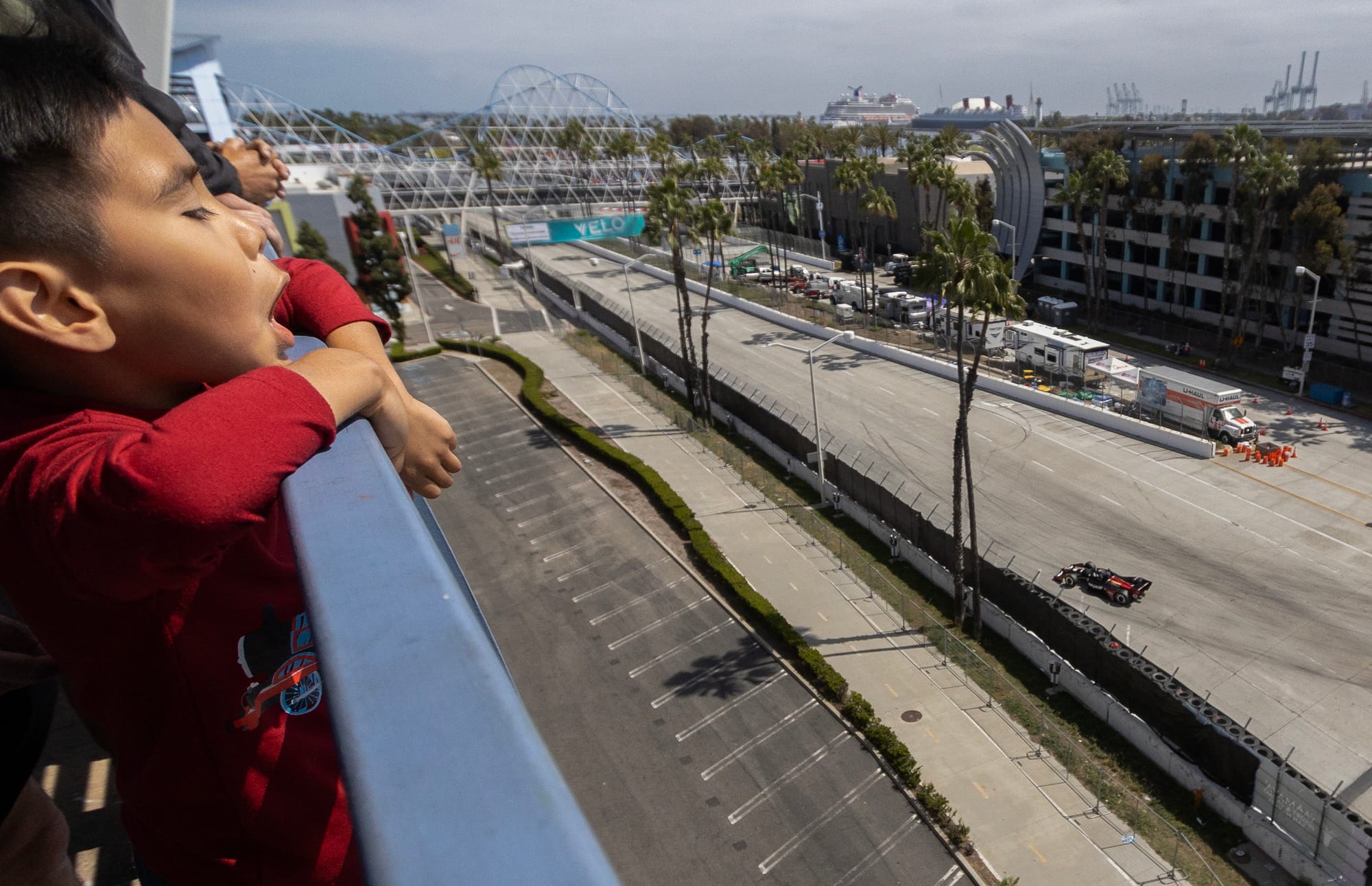 A boy watches a race car below him.