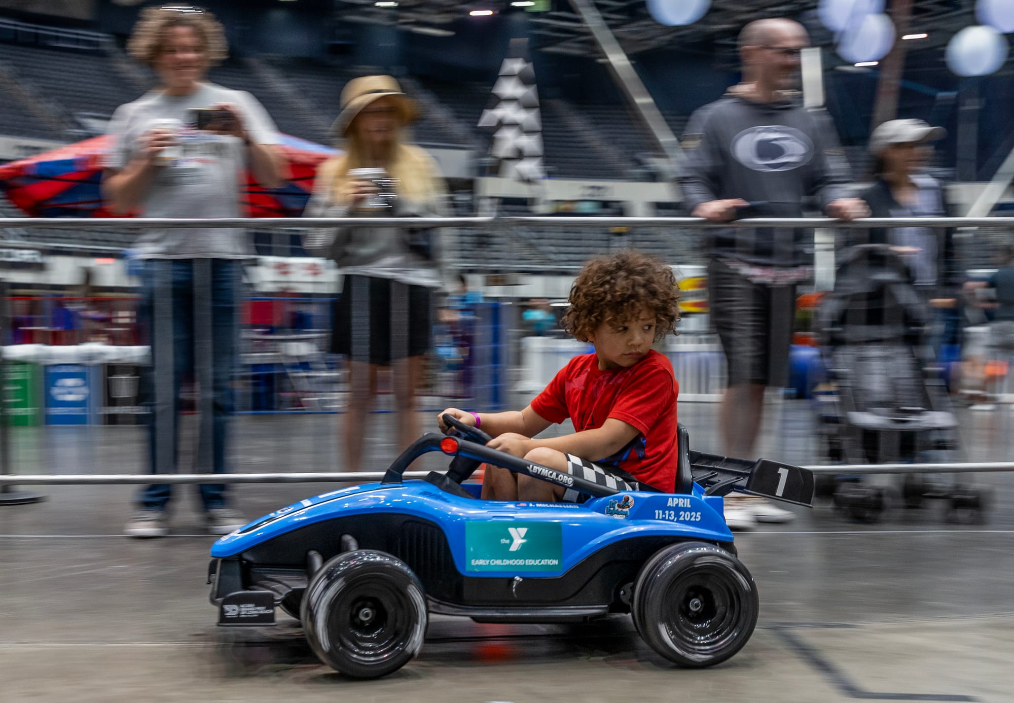 A boy in a red shirt drives a blue go-kart.