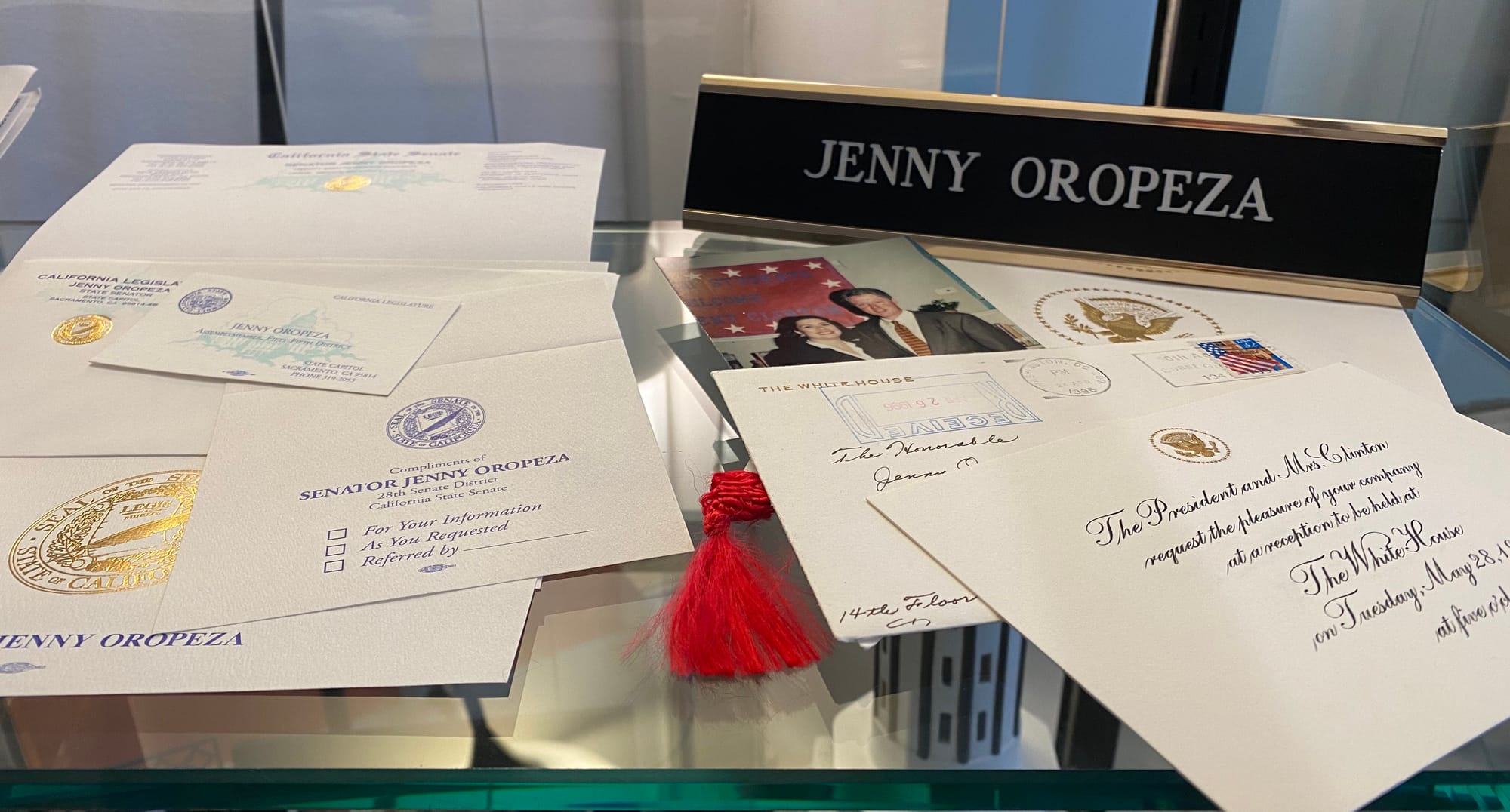  A glass shelf with papers, a photo and a sign saying "Jenny Oropeza."