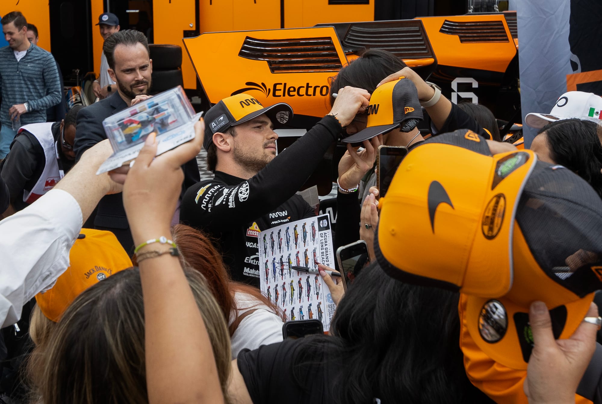 A man signs a person's hat.