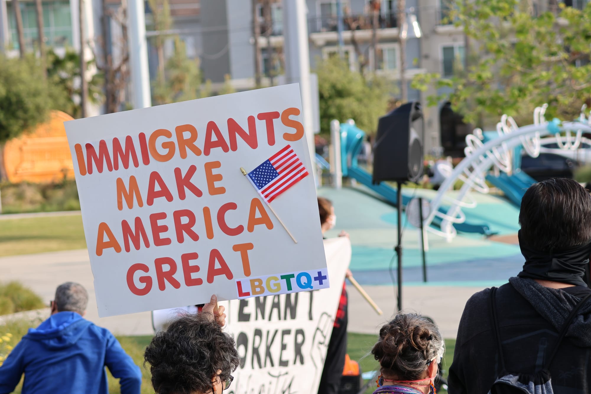 People stand near a sign saying “immigrants make America great.”