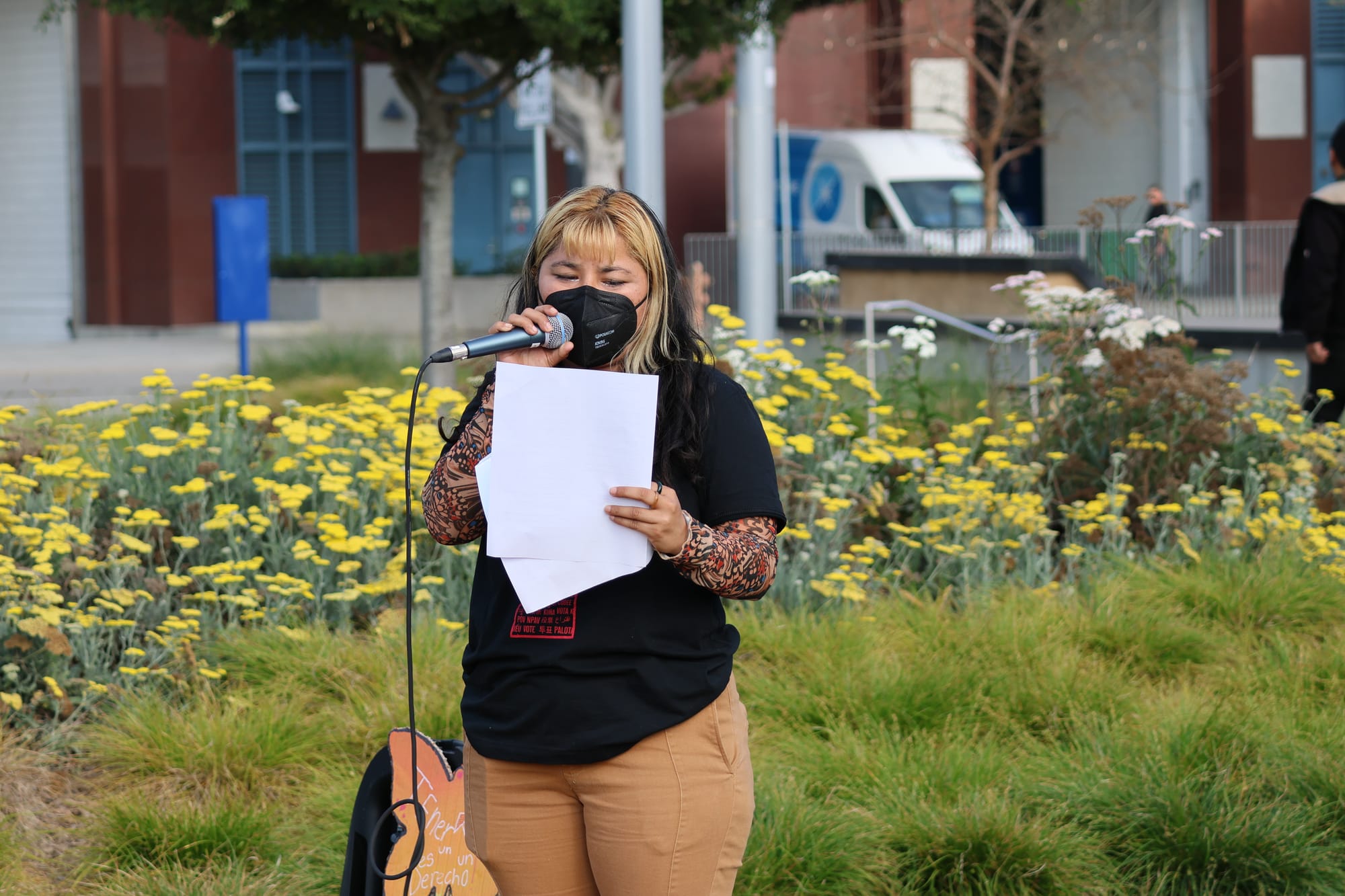 A woman wearing a black shirt speaks at a microphone. 