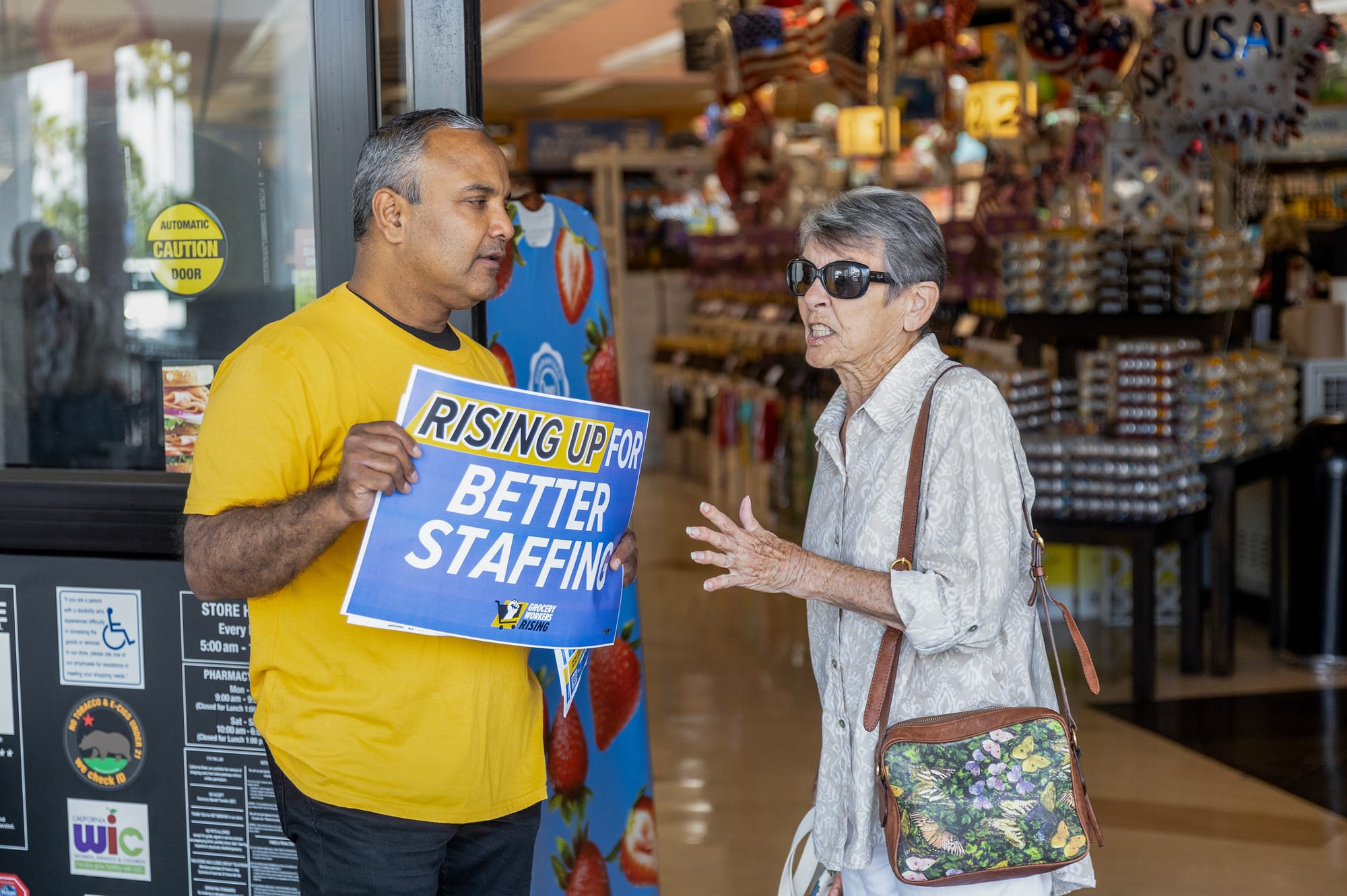 A woman sneers at a man in a yellow shirt holding a sign saying "Rising up for better staffing."