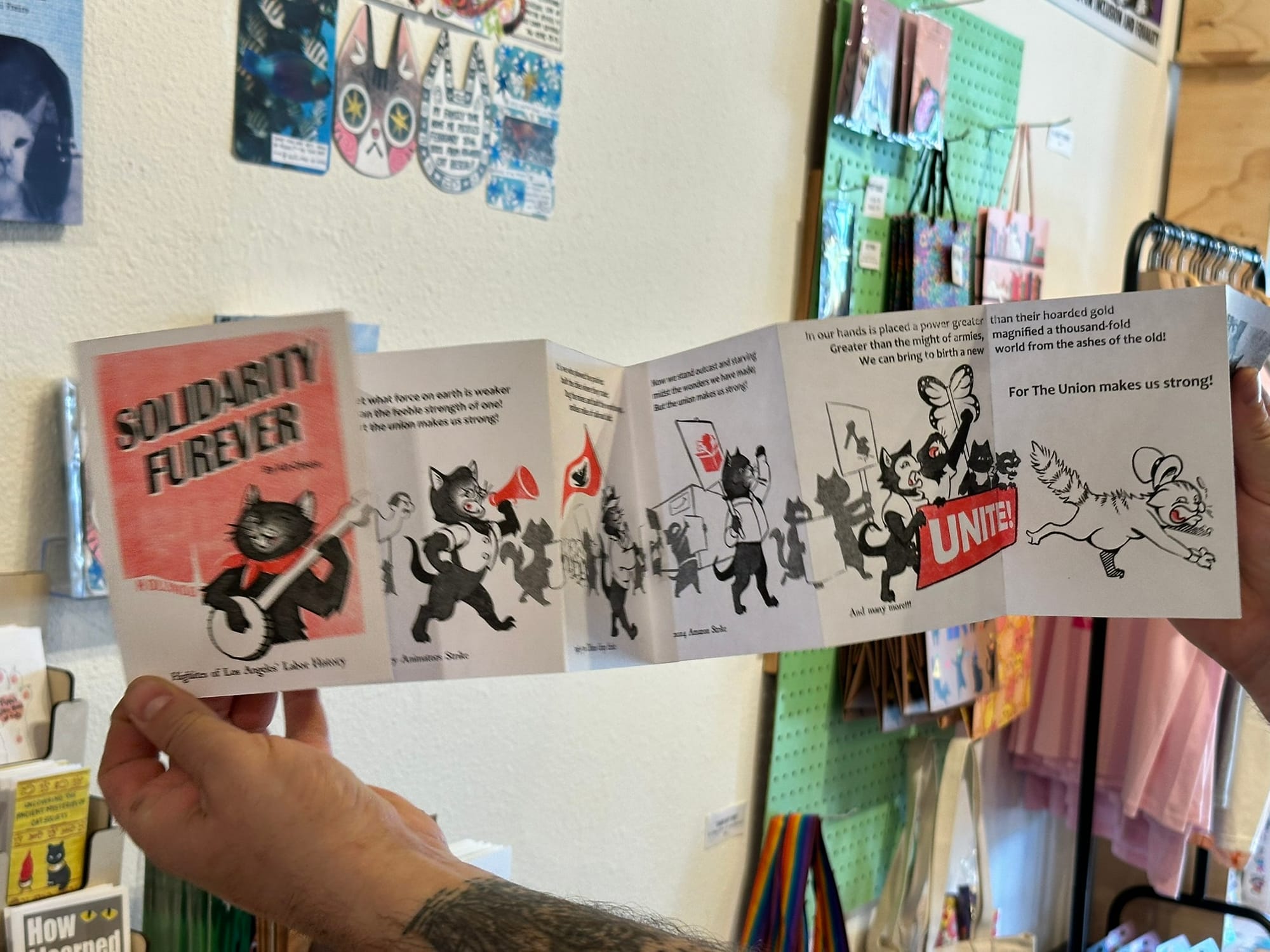 Two hands holding open an accordion-like zine.