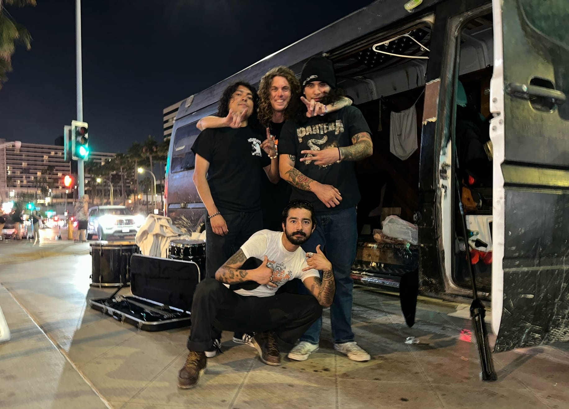 Four guys pose in front of top a van at night.