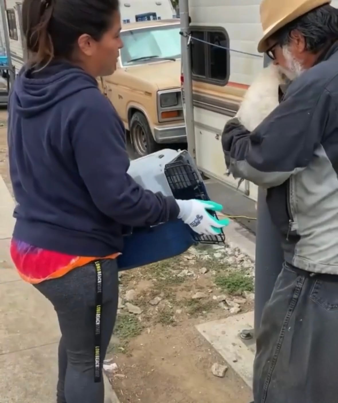 A woman holds a small animal carrier.