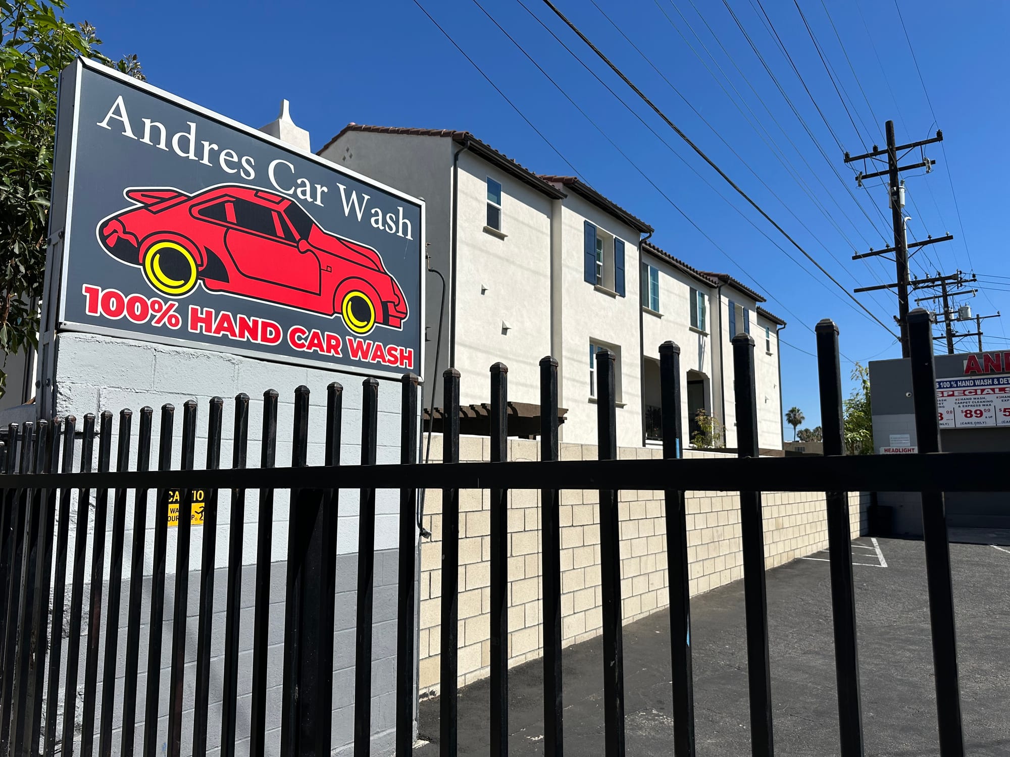 A sign saying "Andres Car Wash" sits over a black iron gage.