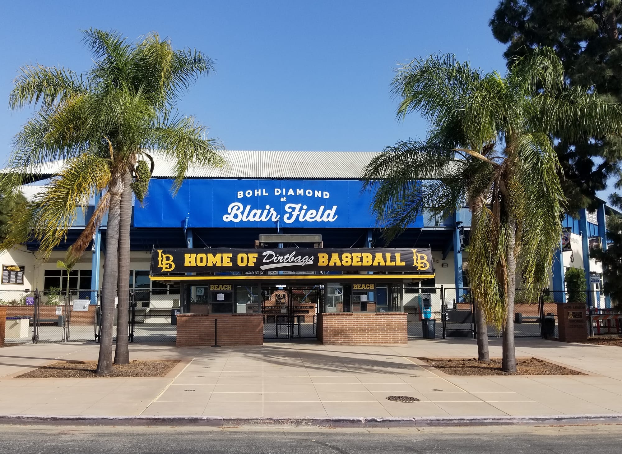The entrance to a stadium flanked by palm trees.