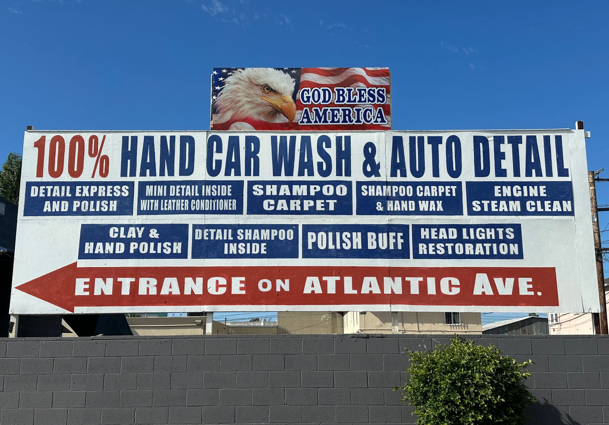 A car wash sign sits on a gray brick wall.