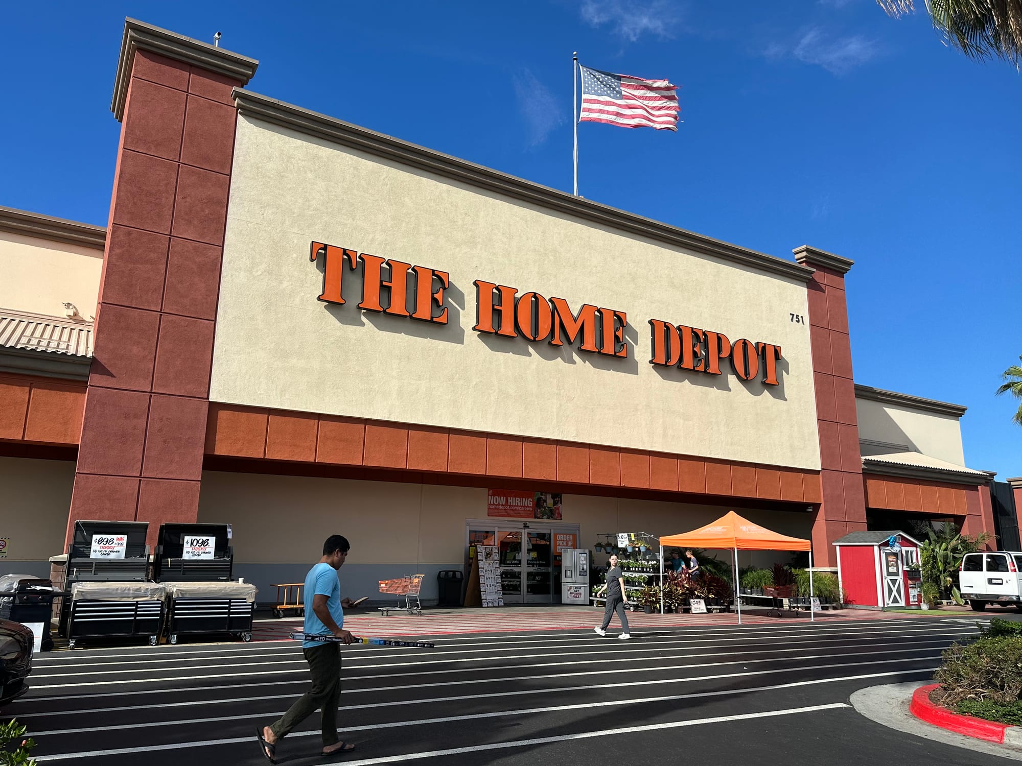 People walk in front of a Home Depot store.