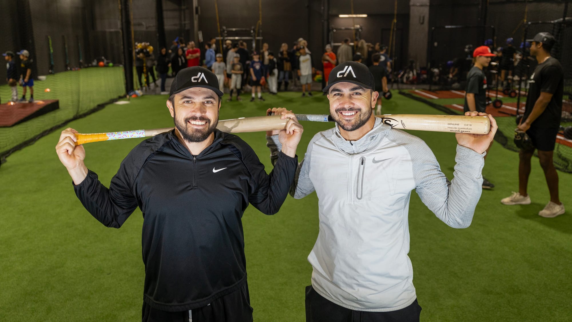 Two men holding baseball bats behind their heads.