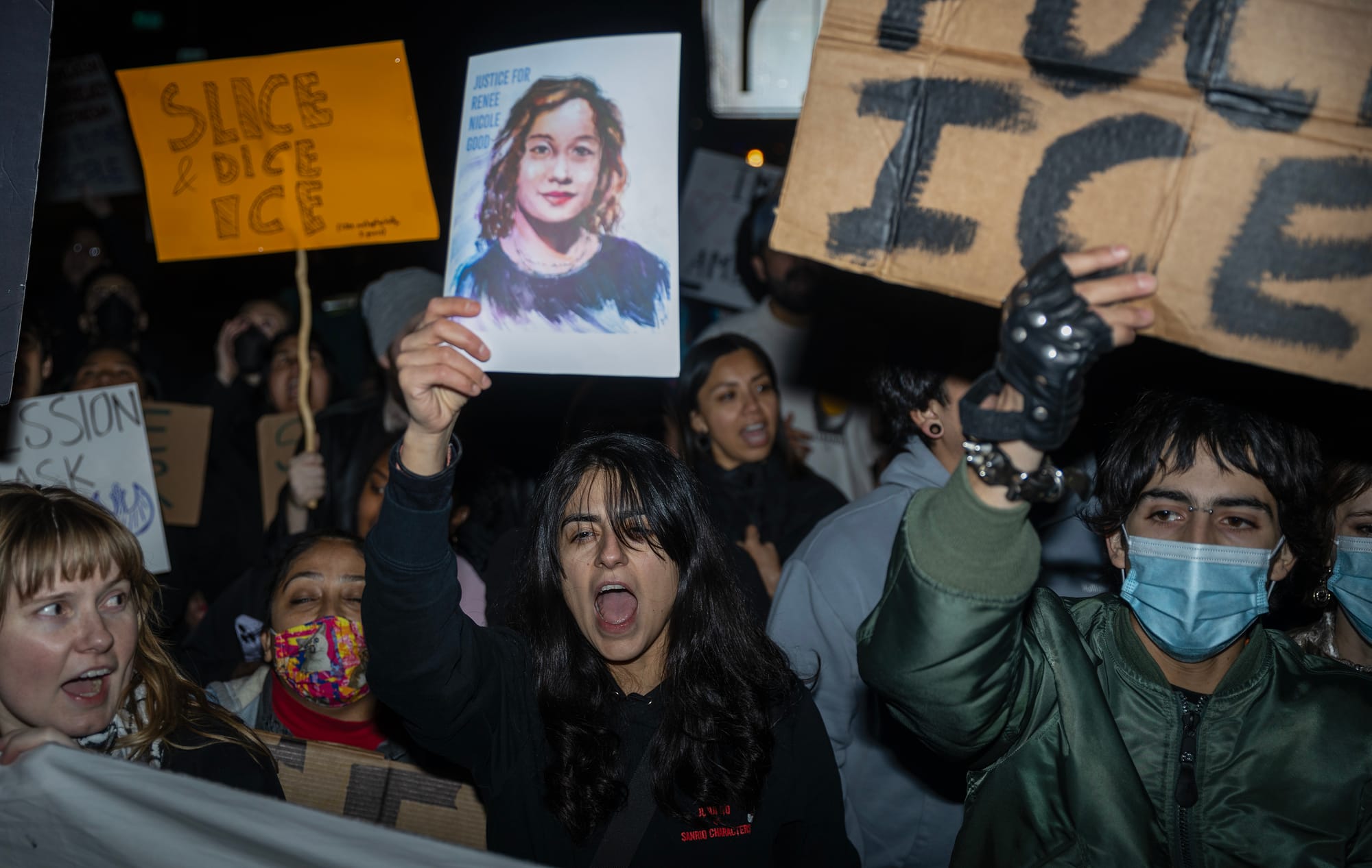People at night hold signs saying "Slice & Dice Ice" and "Fuck Ice."