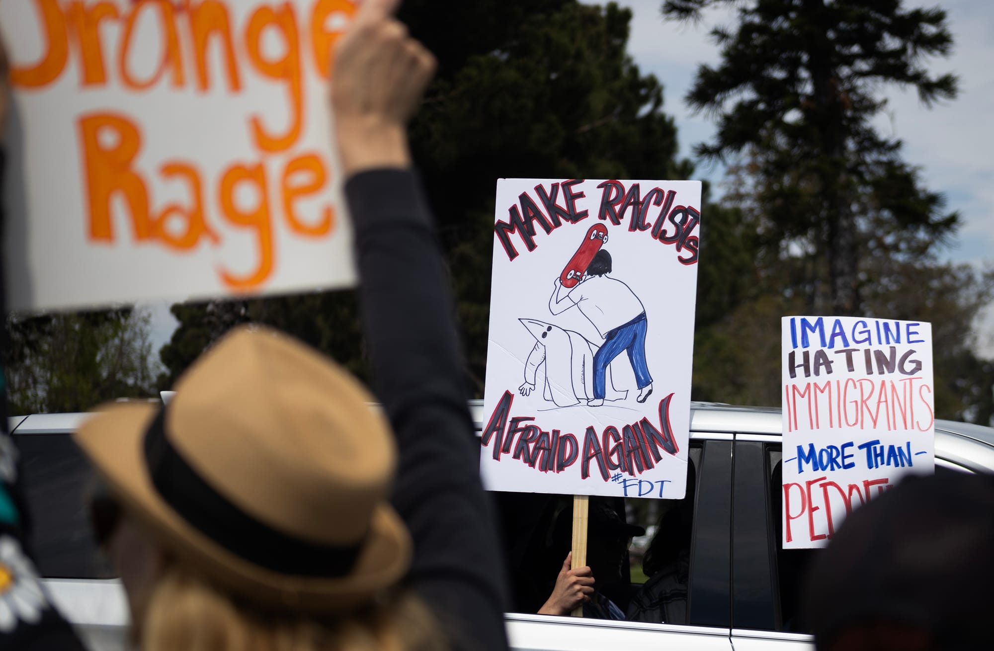 People hold signs saying "Orange Rage," "Make Racists Afraid Again" and "Imagine hating immigrants more than pedophiles."
