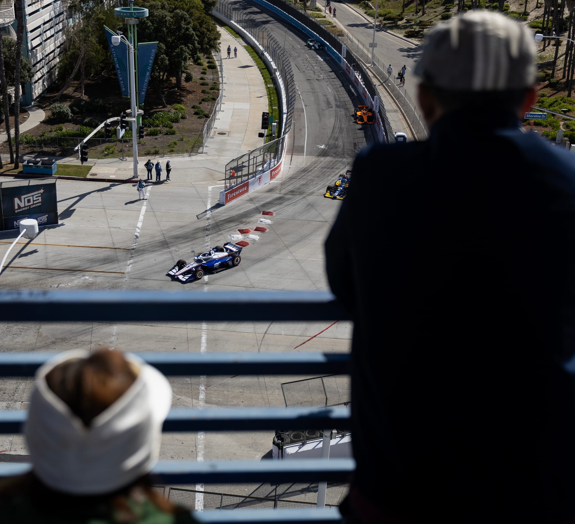 People watch race cars speed along a track.
