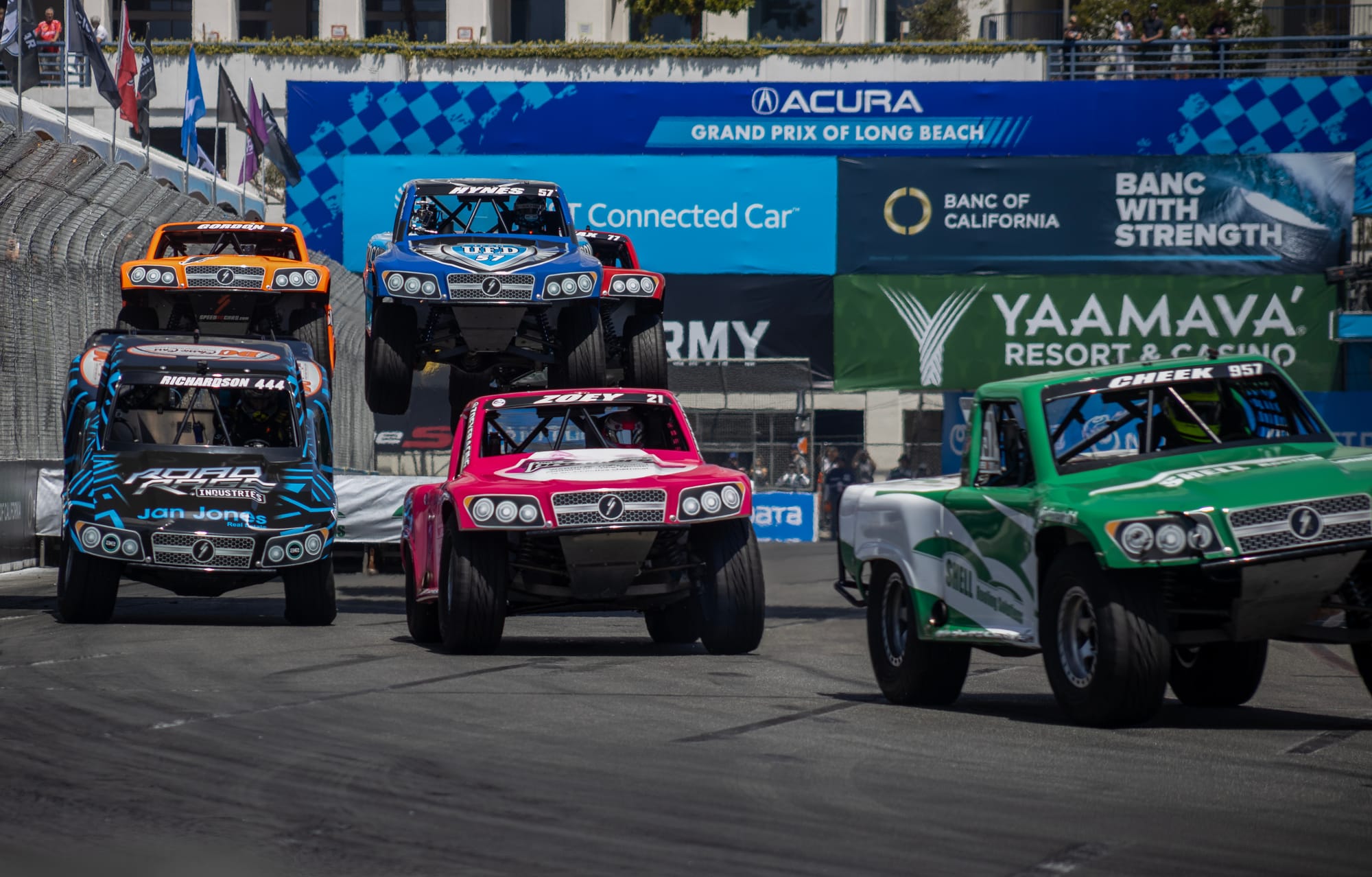 Three trucks speed along a race truck.