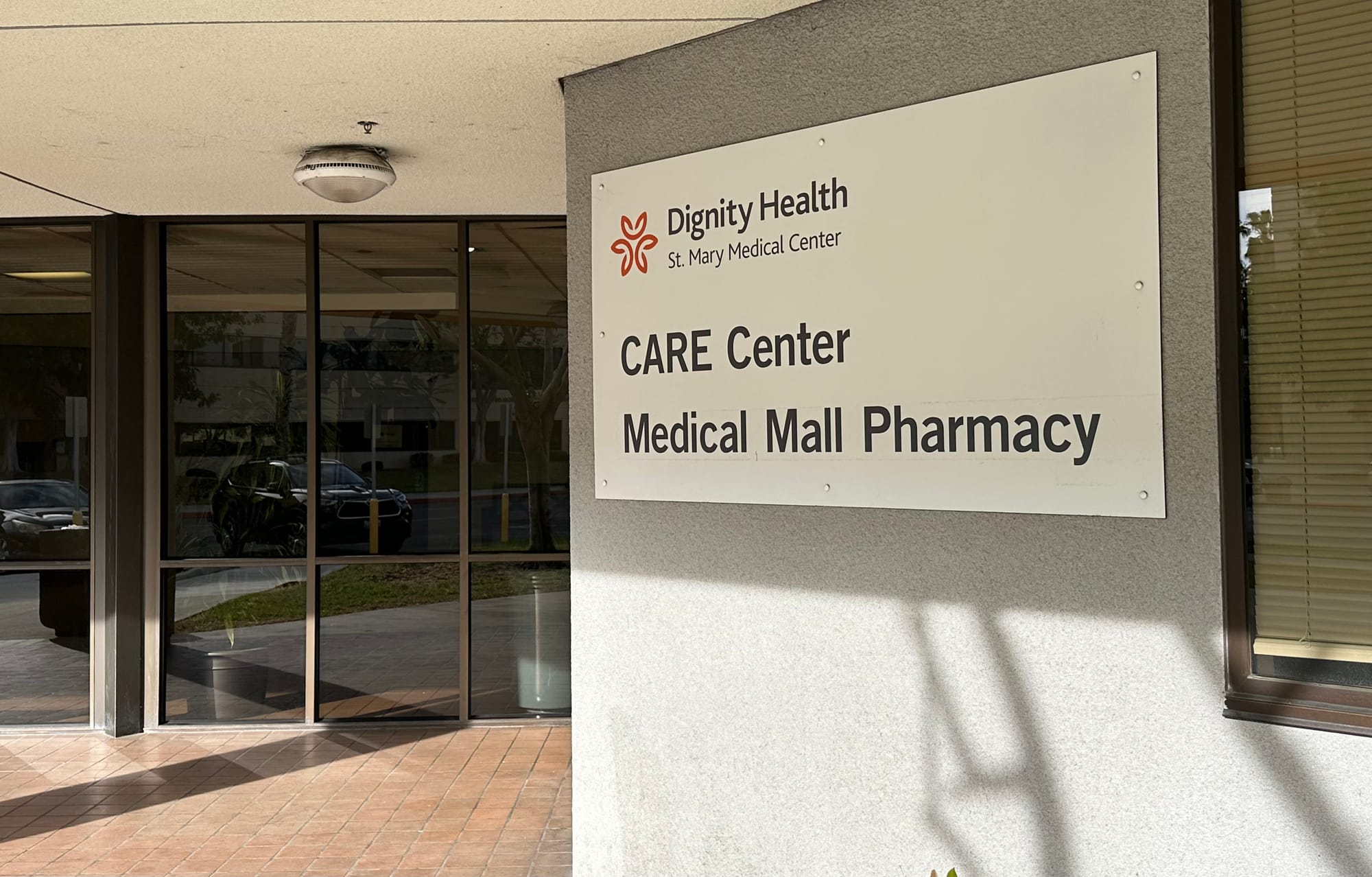 A sign outside a building says "Dignity Health. St. Mary Medical Center. CARE Center. Medical Mall Pharmacy."
