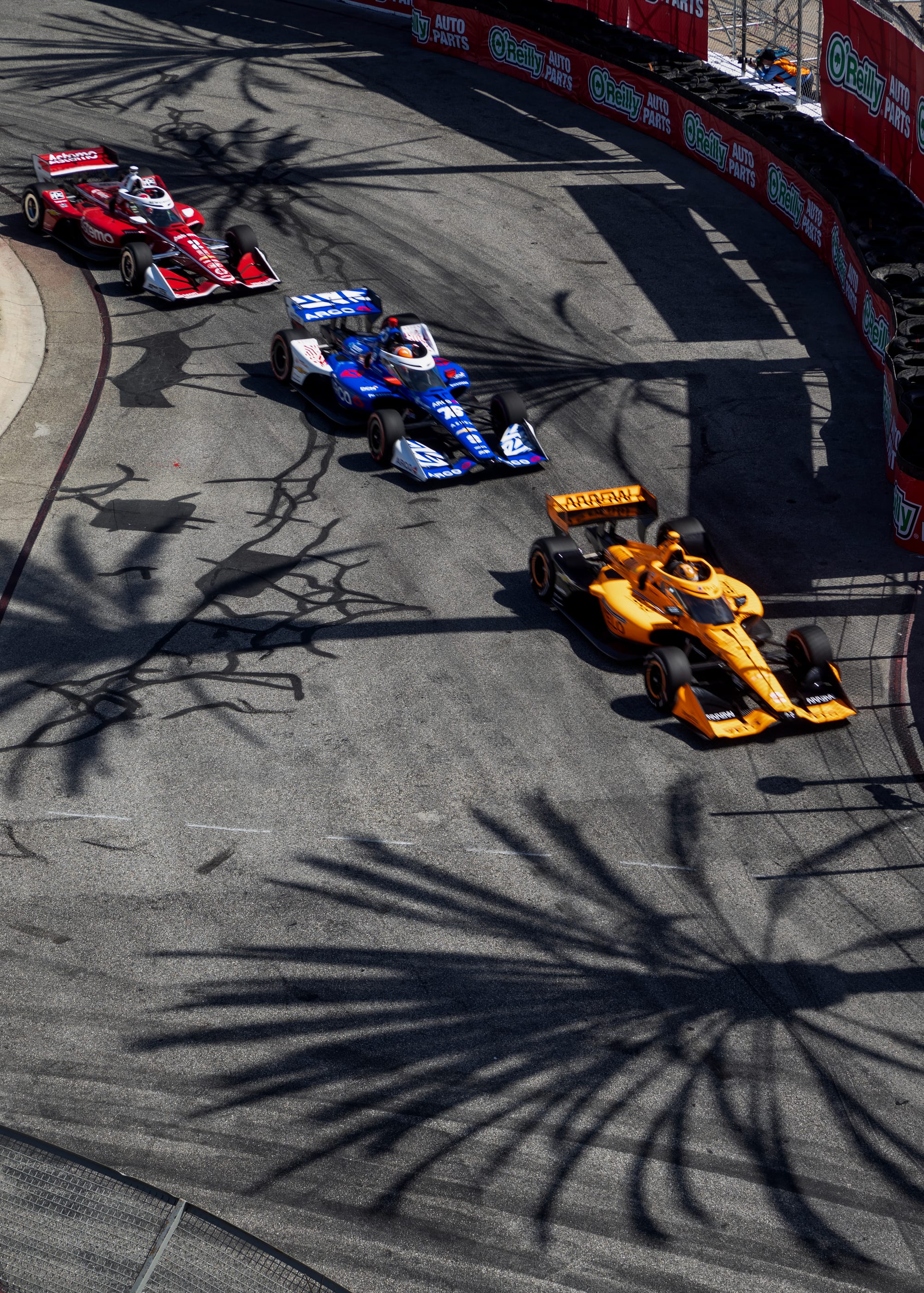 Three race cars line up on a race track.