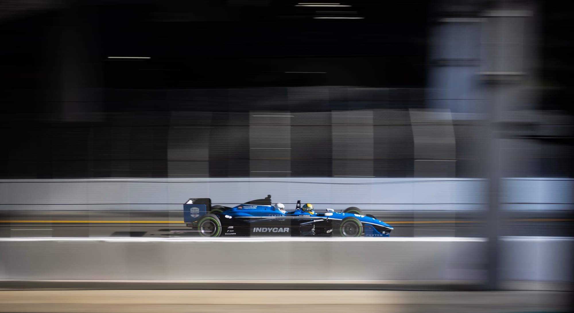 A blue race car speeds down a race track.