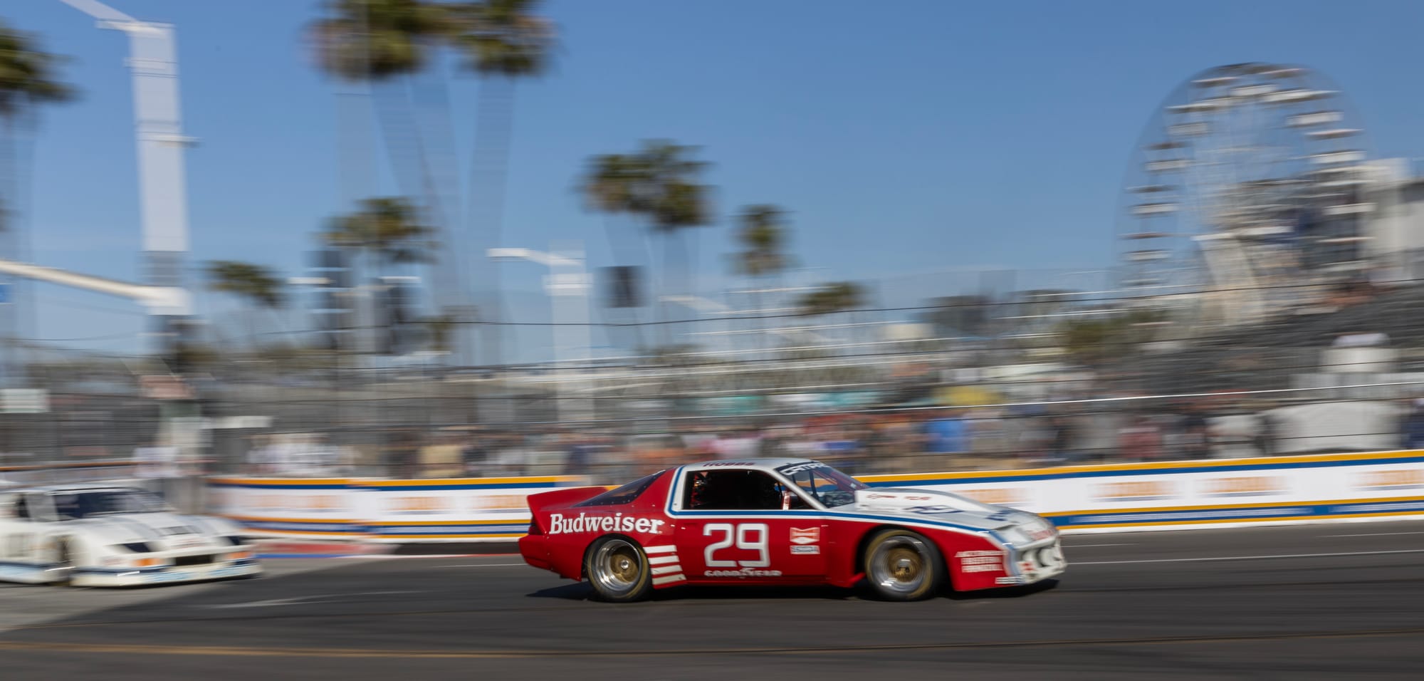 A red and white sports car speeds on a race track.
