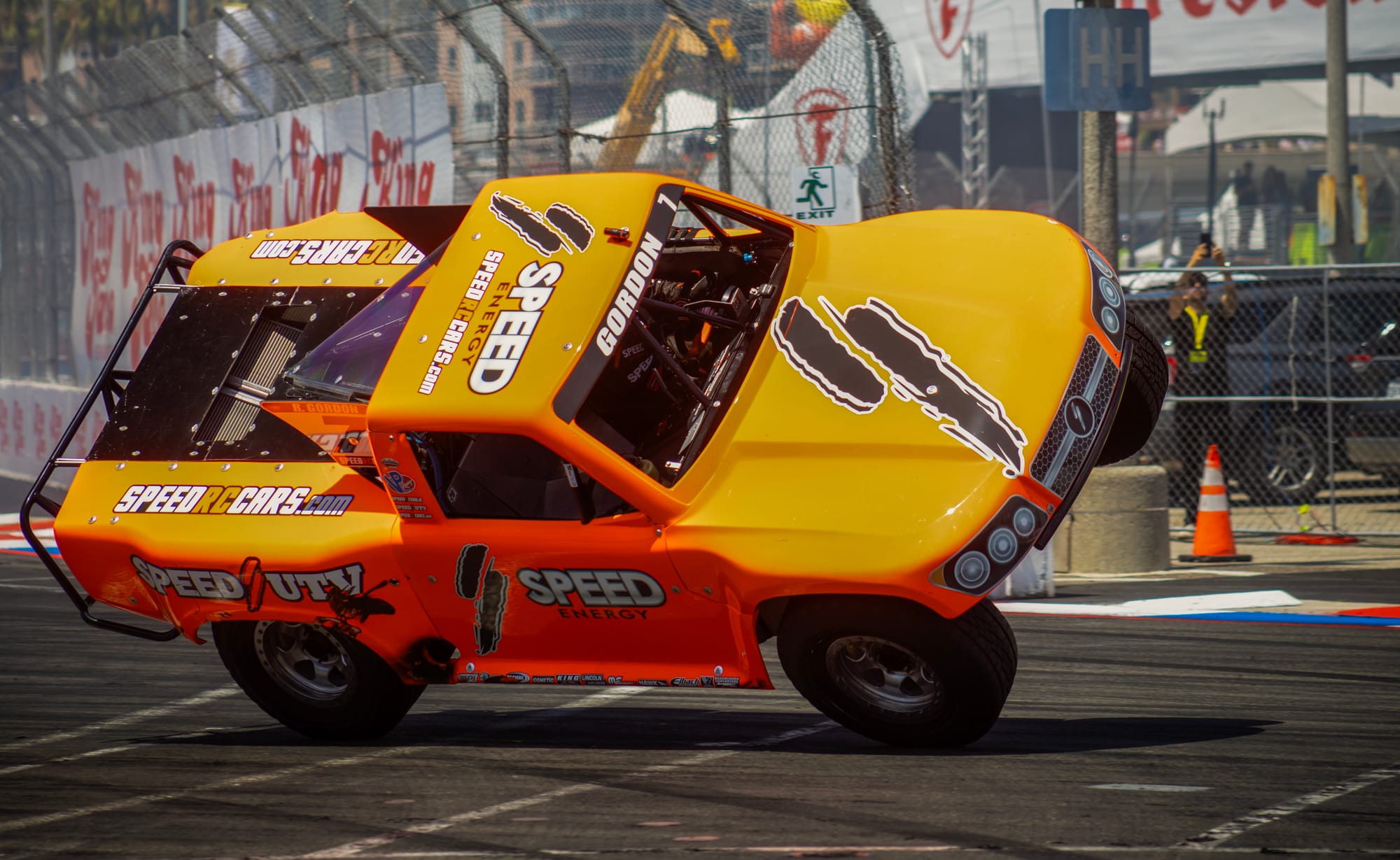 A yellow and orange truck drives on two wheels.