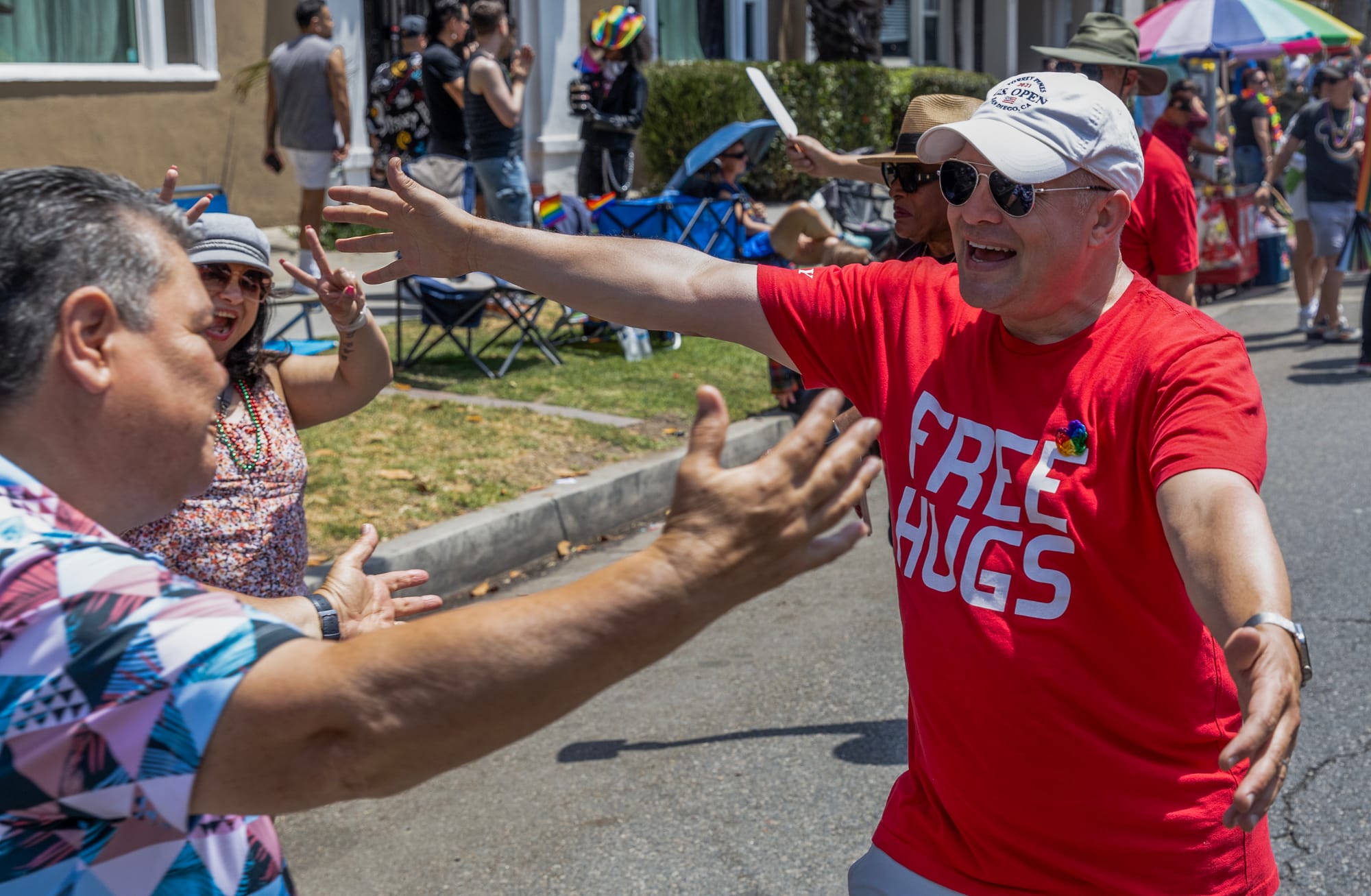 A man goes to hug another man in a red shirt that says "Free hugs."