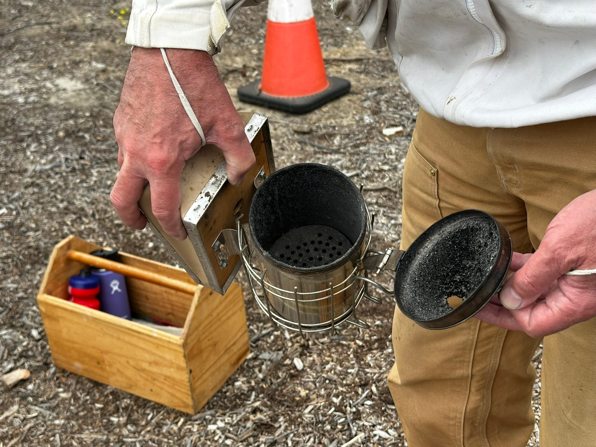 A man holds a small can that is open to show it is covered in black soot inside.