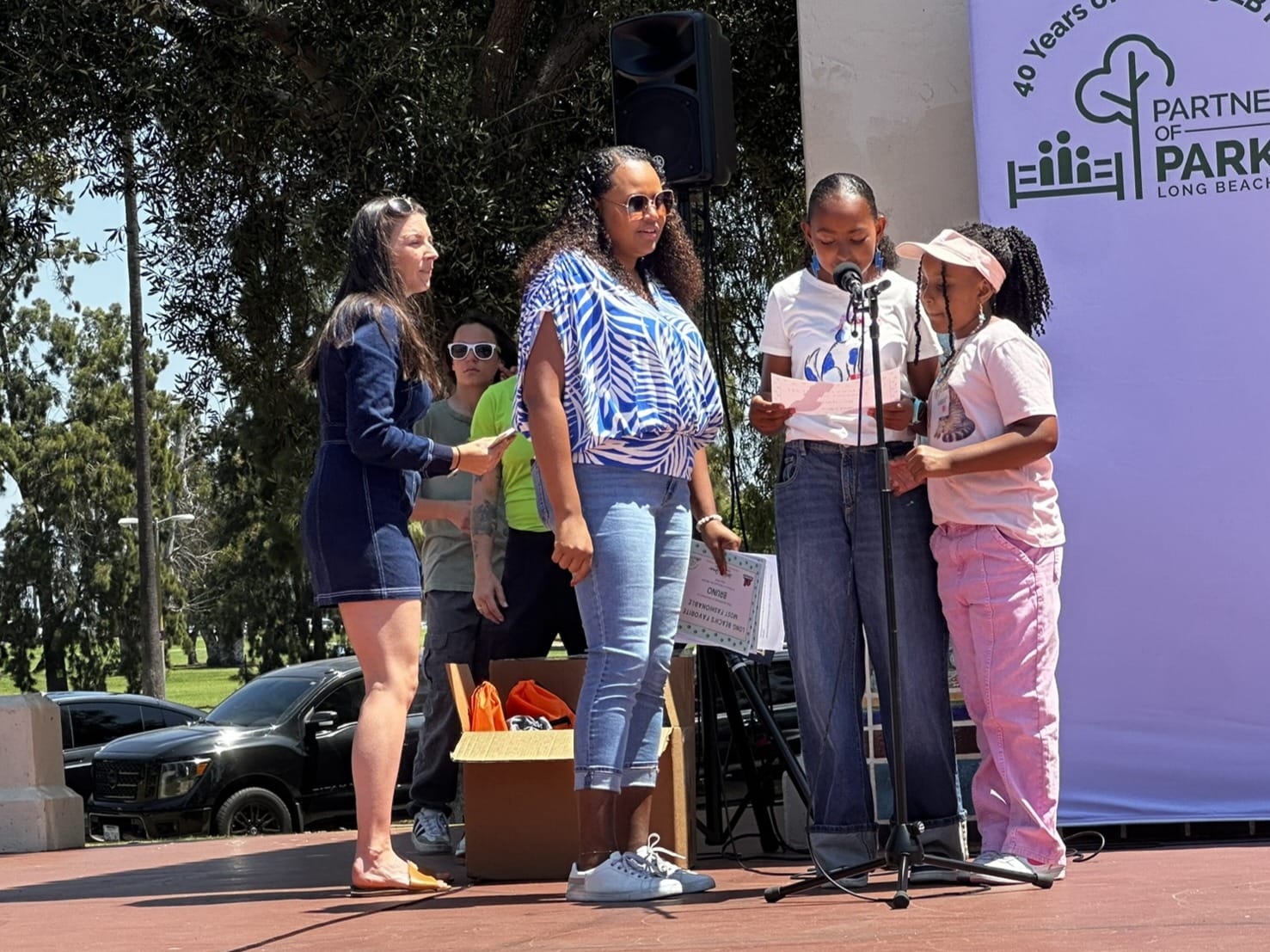 A group of adults and teens stands on a stage at a microphone.