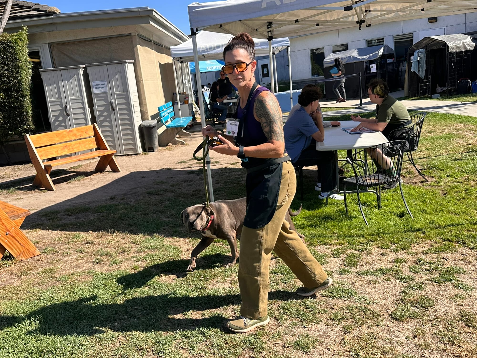 A woman walks outside next to a sweet dog on a leash.