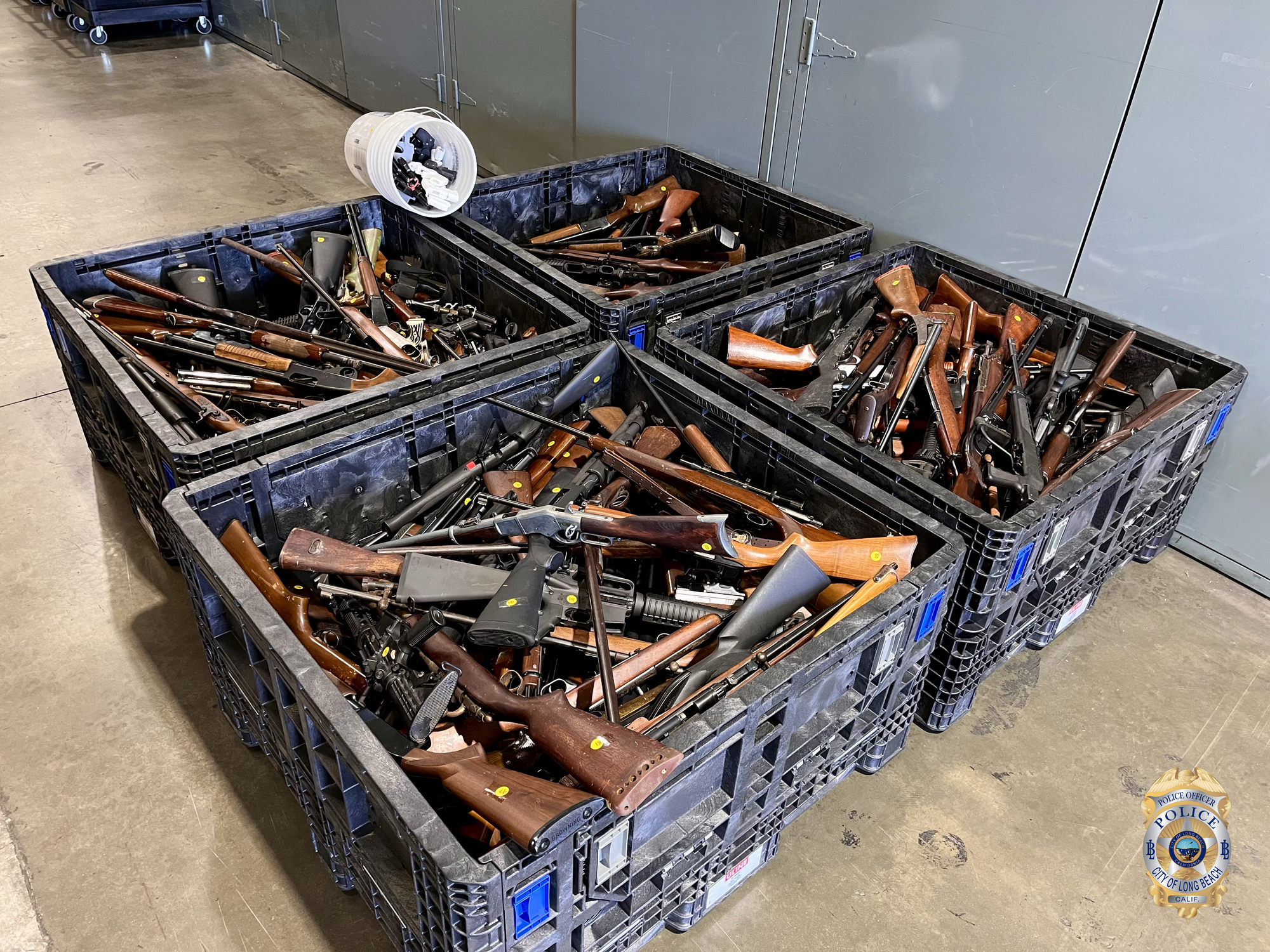 Four crates loaded with rifles sit next to each other in a warehouse.