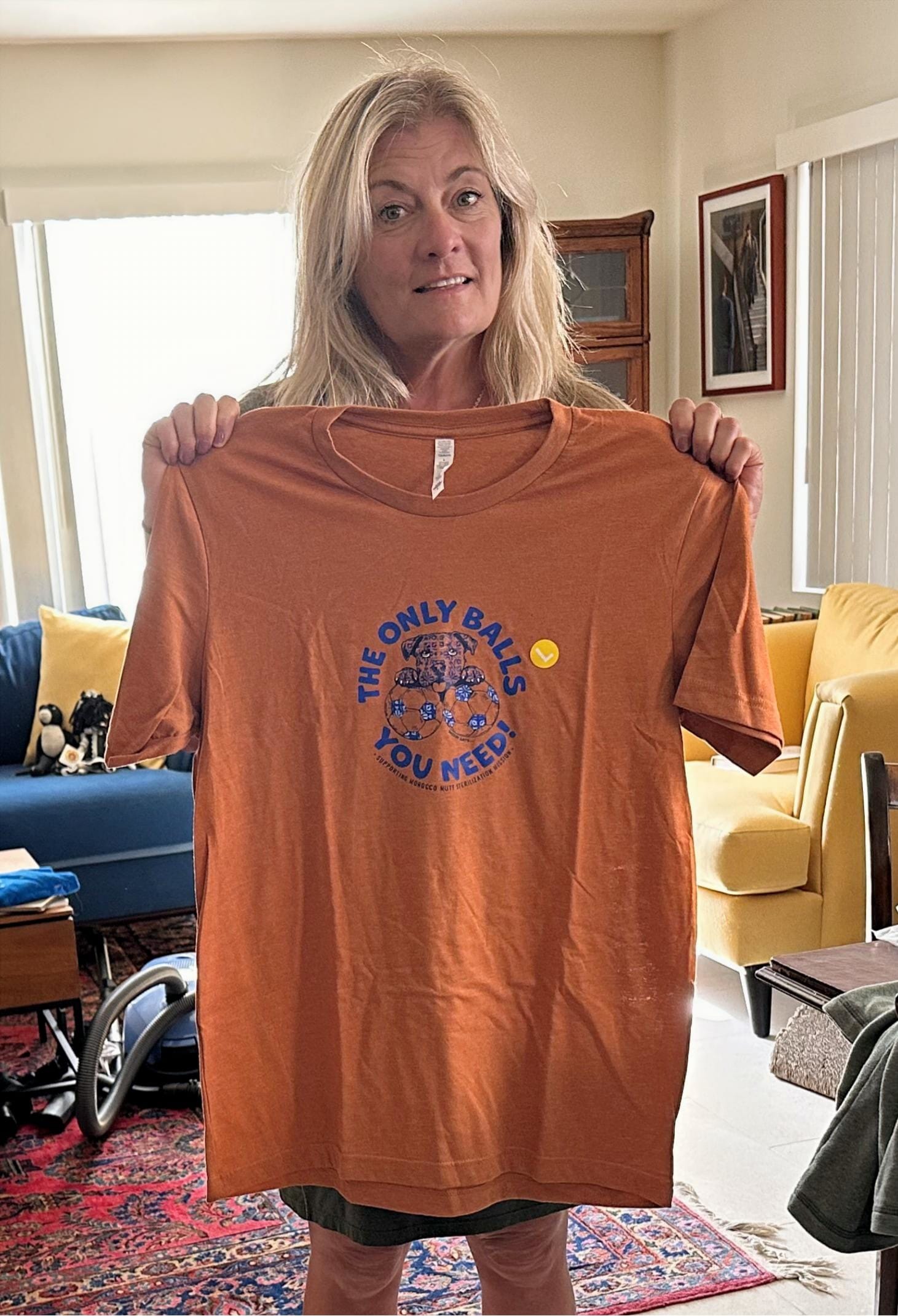 A woman holds up an orange shirt that says "The only balls you need!"
