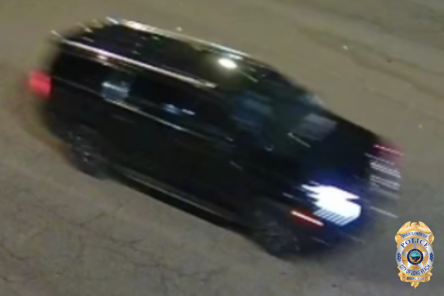 Blurry photo of a black sports utility vehicle traveling on a road at night.