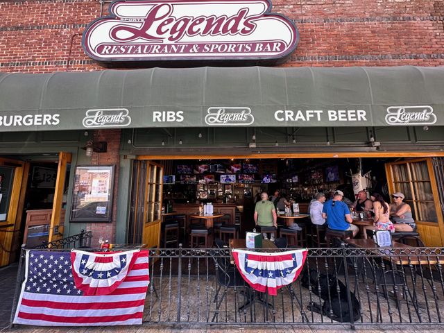 People sitting in an open-air restaurant in front of a black dog and an American flag on a black railing