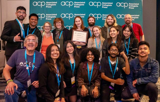 A large group of college-aged students and their teachers post for a picture at an award ceremony.